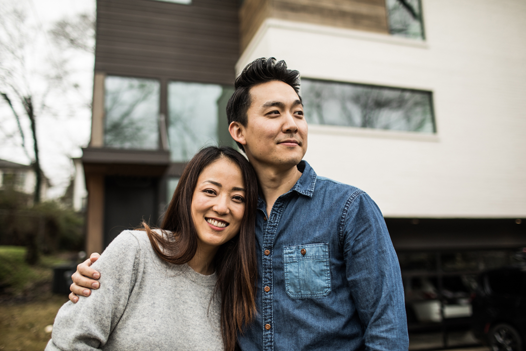 A smiling couple standing close together outside their newly electrified house