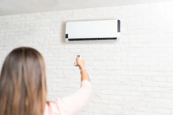 Woman turning on a mini-split heat pump using a remote