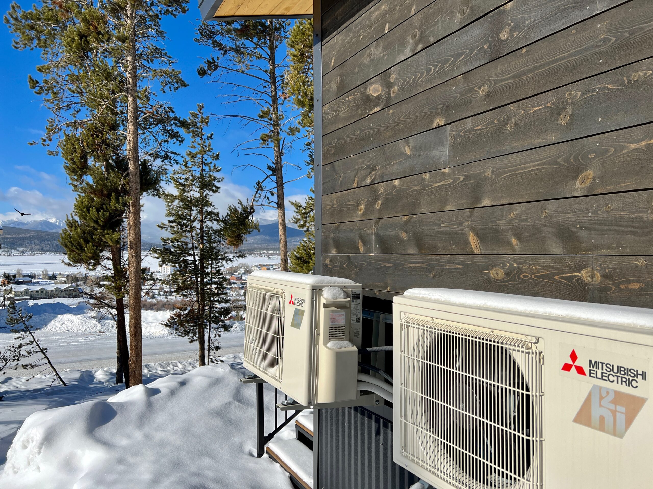 Two Mitsubishi condensers outside a home during winter