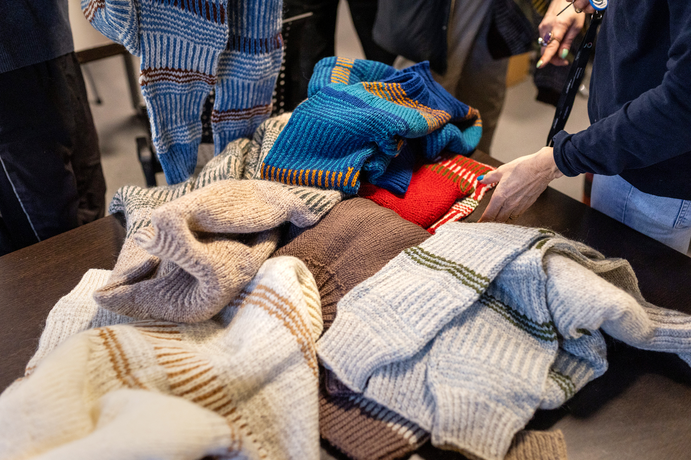Foto: En kvinnehånd leter blant ullgensere i mange farger.