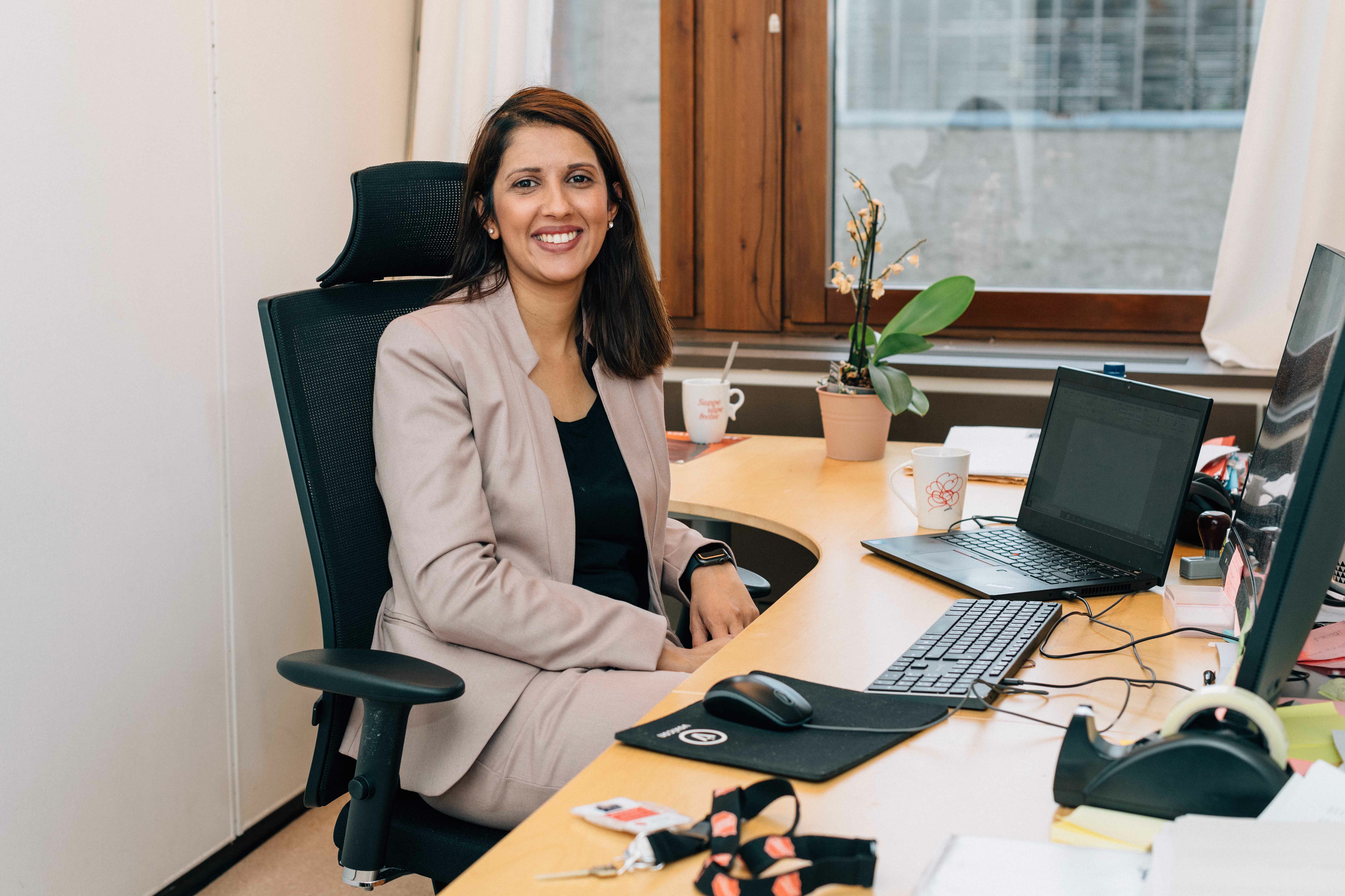 Advokat Aishah Ahmed i Frelsesarmeen. Sitter på kontoret sitt på en kjontorstol ved pulten.