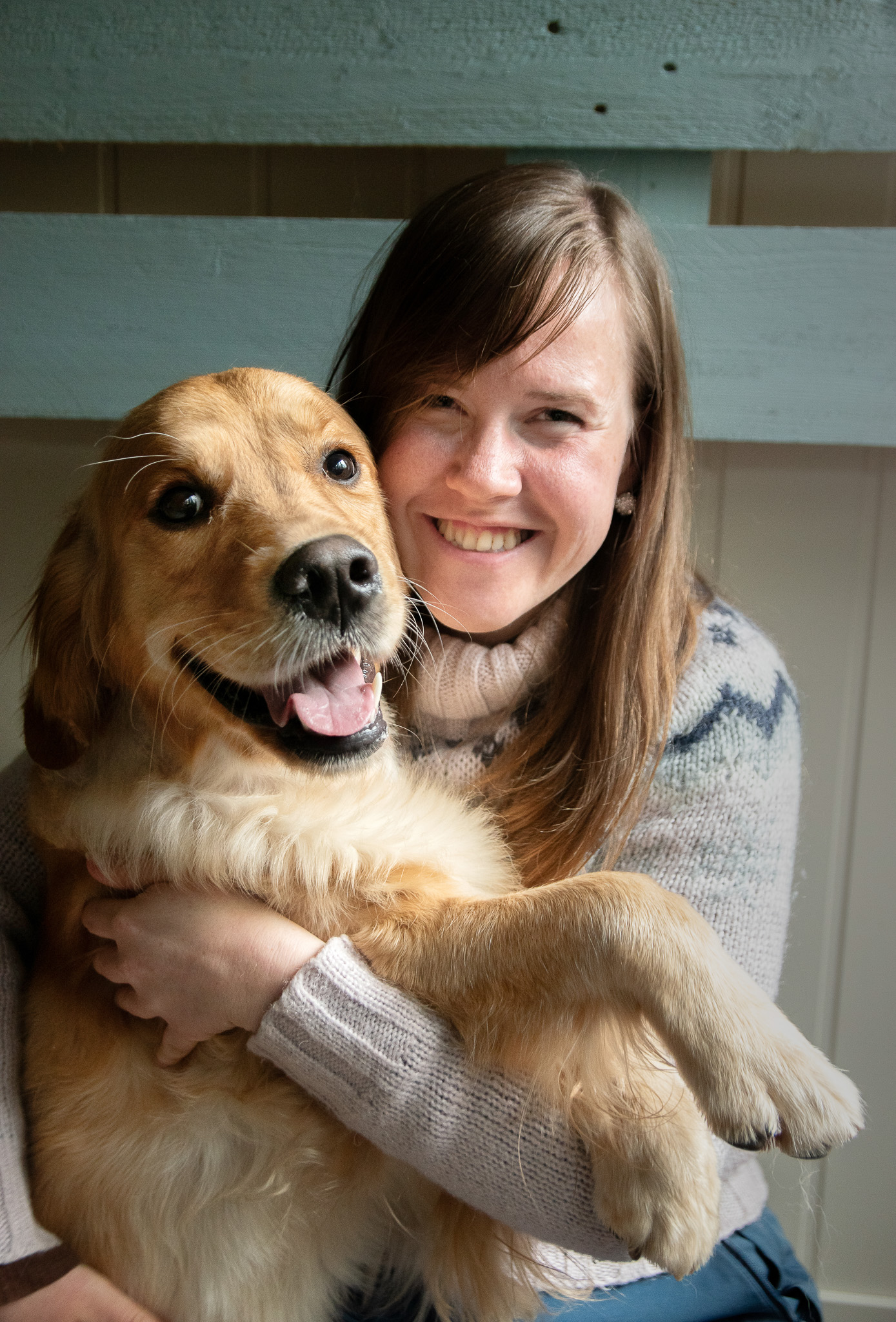 Kvinne klemmer en hund, begge smiler bredt.