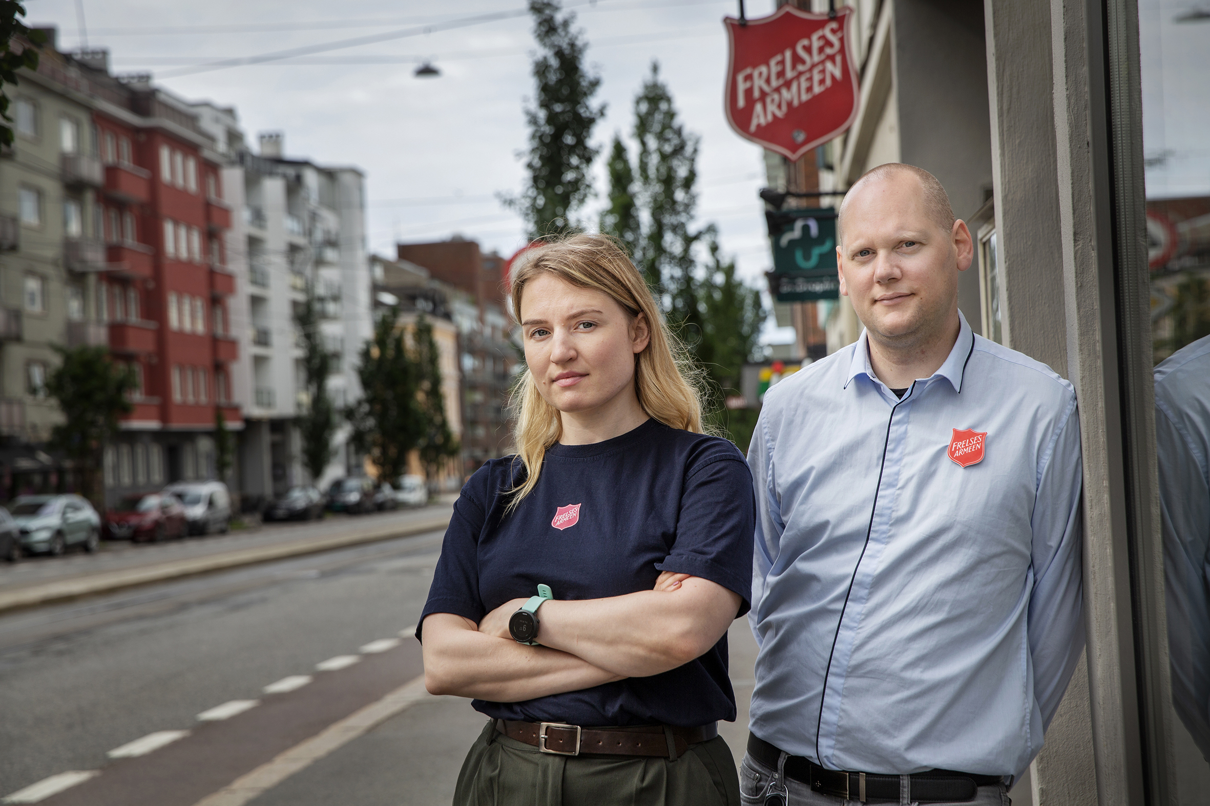 Foto: Den samme kvinnen i mørk T-skjorte og mannen i lys skjorte står sammen, men denne gangen utenfor Frelsesarmeens bygg i Kirkegata i Oslo.