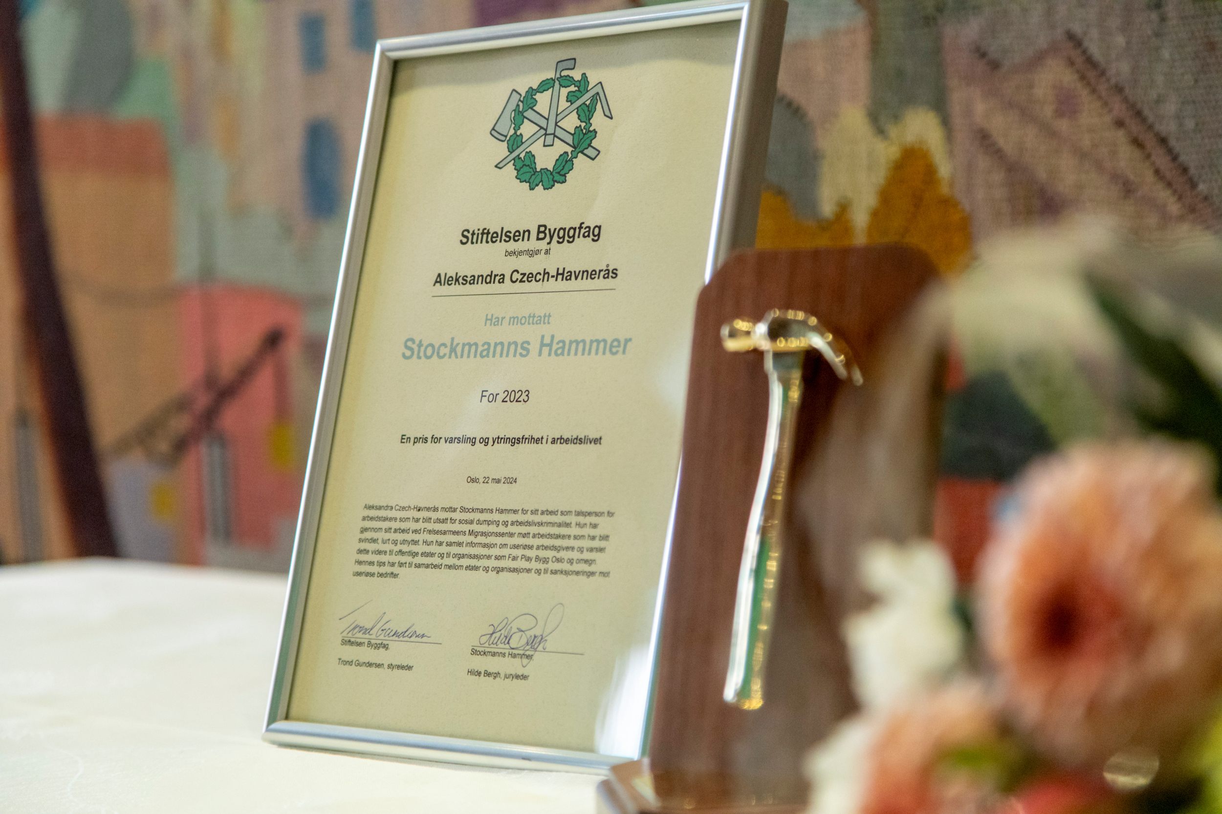 Foto: Nærbilde av et bord med hvit duk på. Der står diplomet i en ramme og prisen og blomsterbuketten ligger klar.