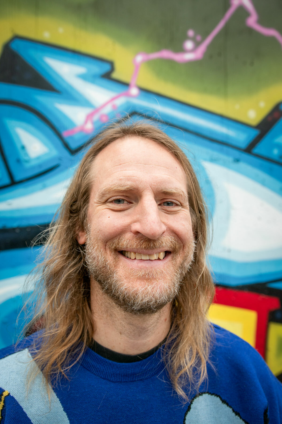 Foto: Nærbilde av blond mann med halvlangt hår og skjegg i Donald-genser.