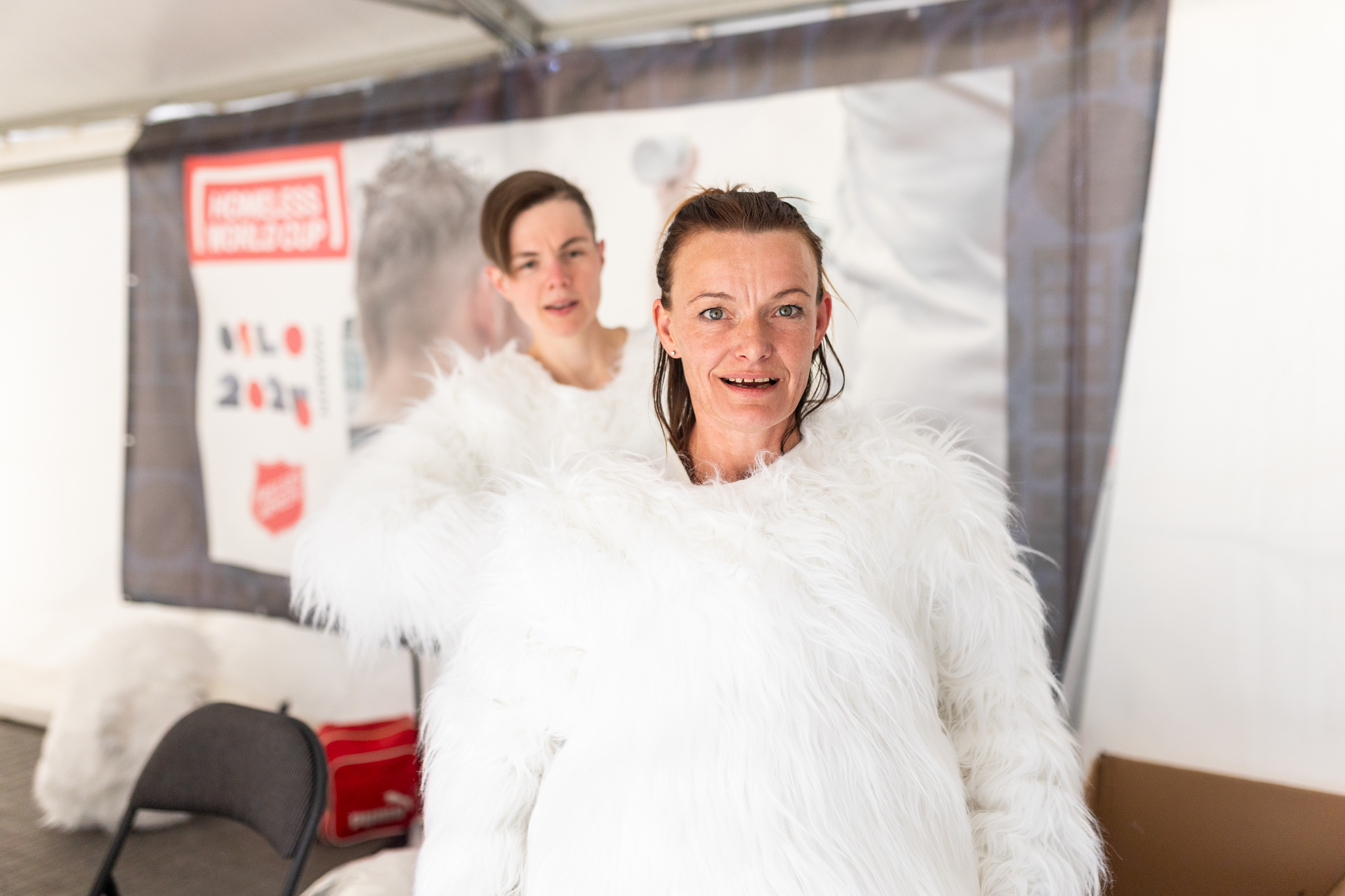 Foto: To kvinner i hvite, fluffy drakter. De holder på å kle på seg maskotene. Isbjørnhodene mangler så her er det to mørkhårede kvinnehoder som stikker opp av draktene.