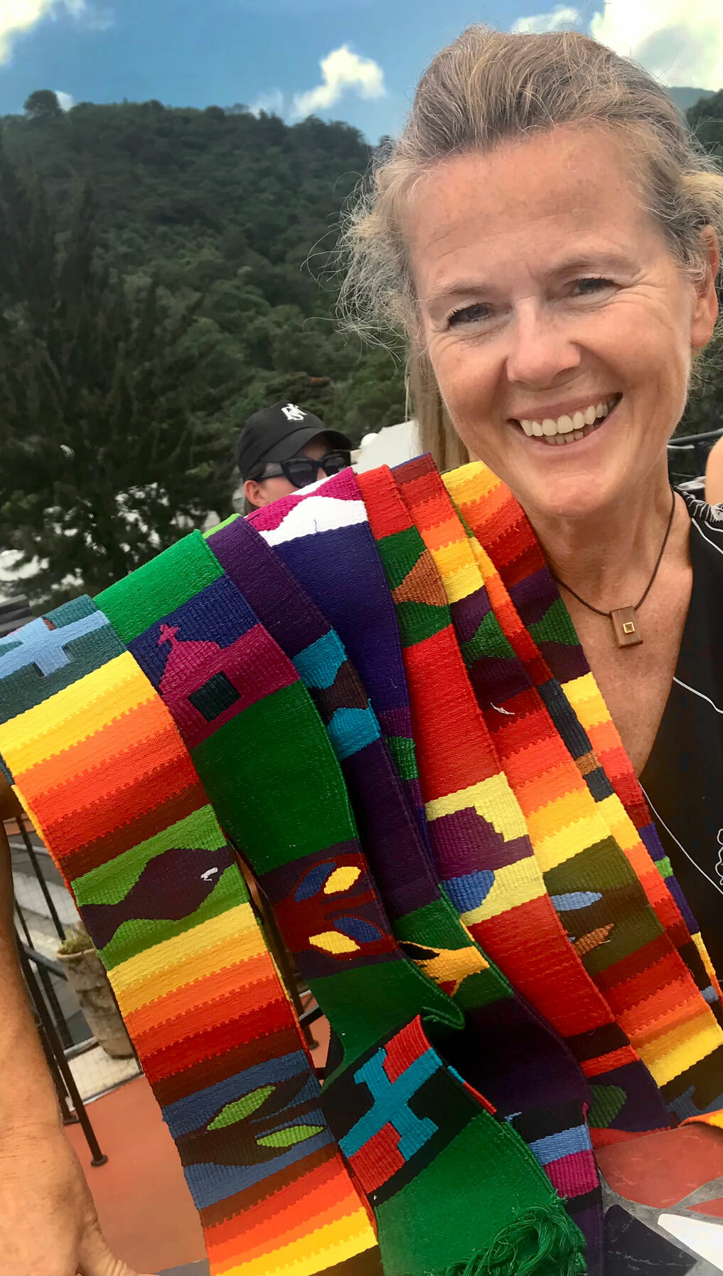 Foto: Norsk kvinne med fargerike, vevde bånd lagt nedover den ene skulderen.