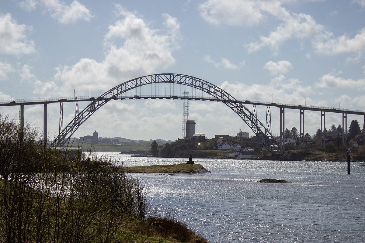 Foto: Gjennom buen til Karmsund bru skimtes Avaldsnes kirke.