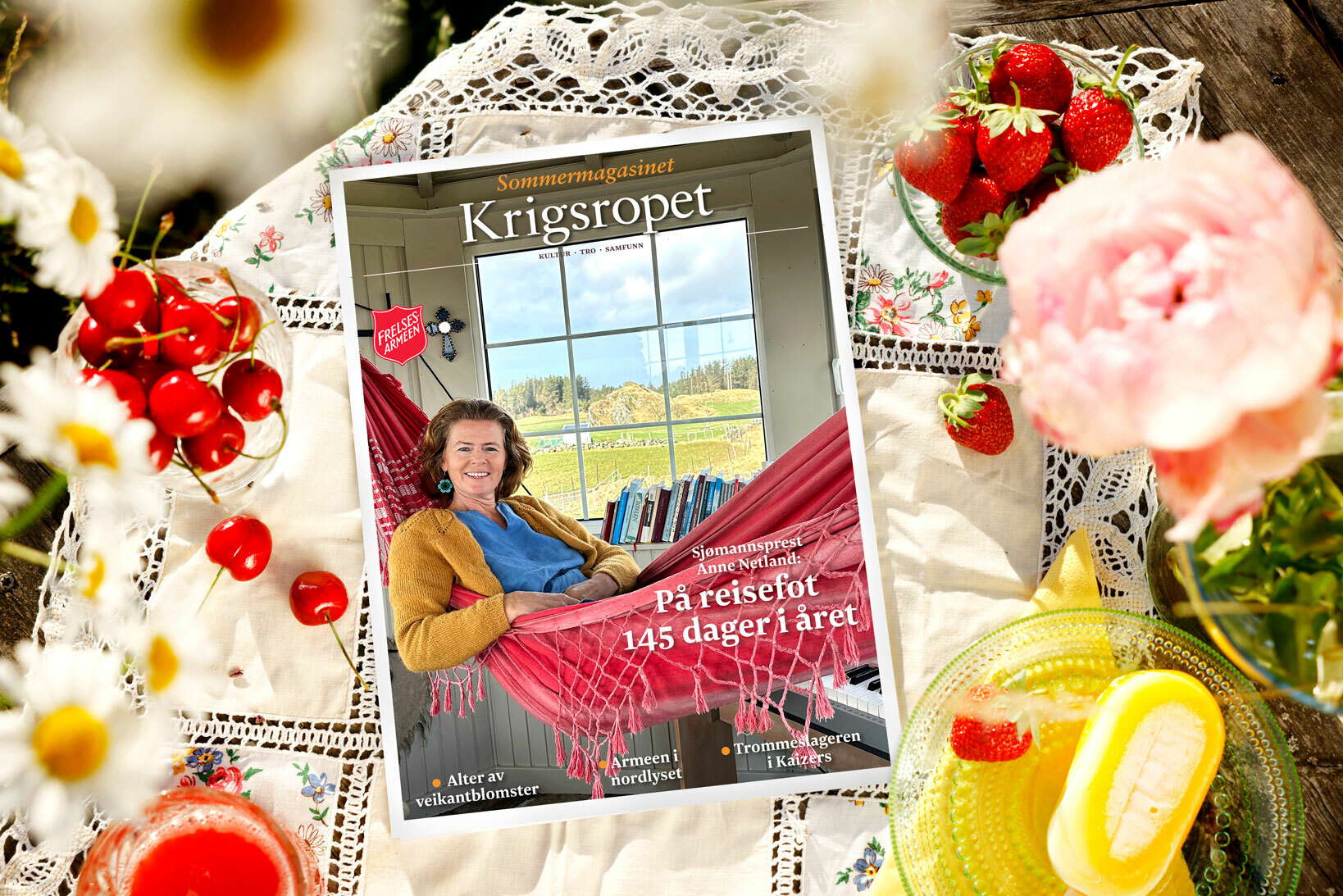 Foto: Fronten på et blad ligger på en sommerlig duk med både kirsebær og blomster.