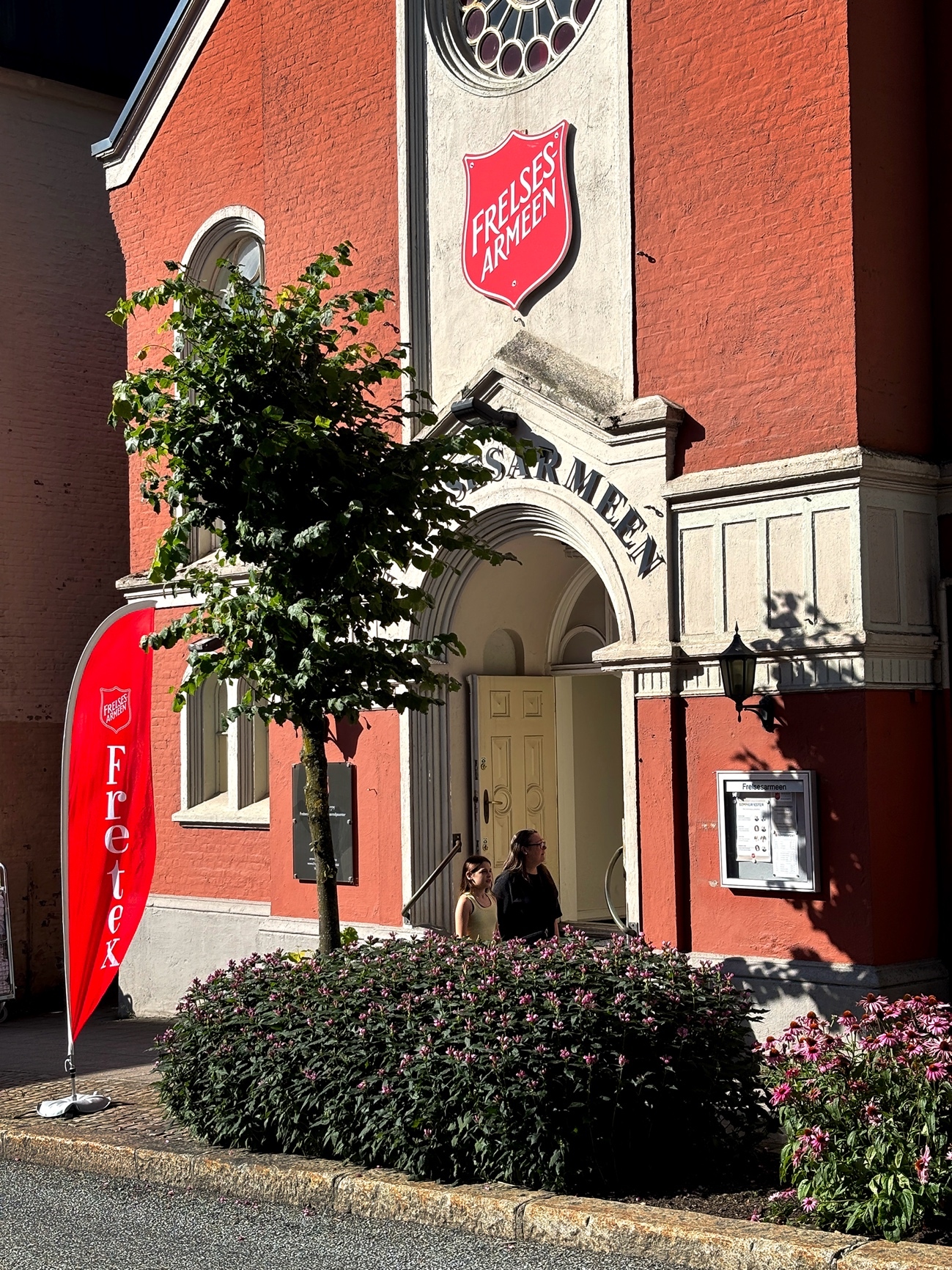 Foto: Eksteriør av kirkelignende murbygg i lakserødt og beige med stor logo fra Frelsesarmeen.