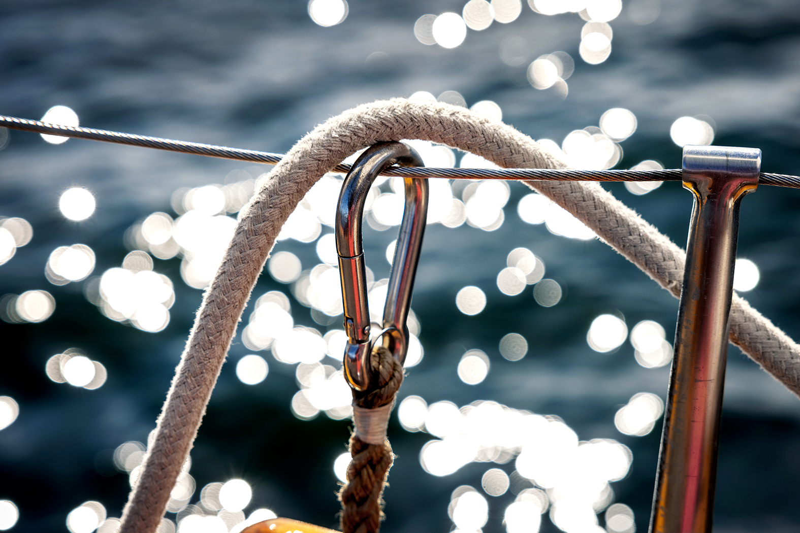 Foto: Tau over en stålvaier på kanten av båtripa. bak sees sjøen. Havet glitrer.