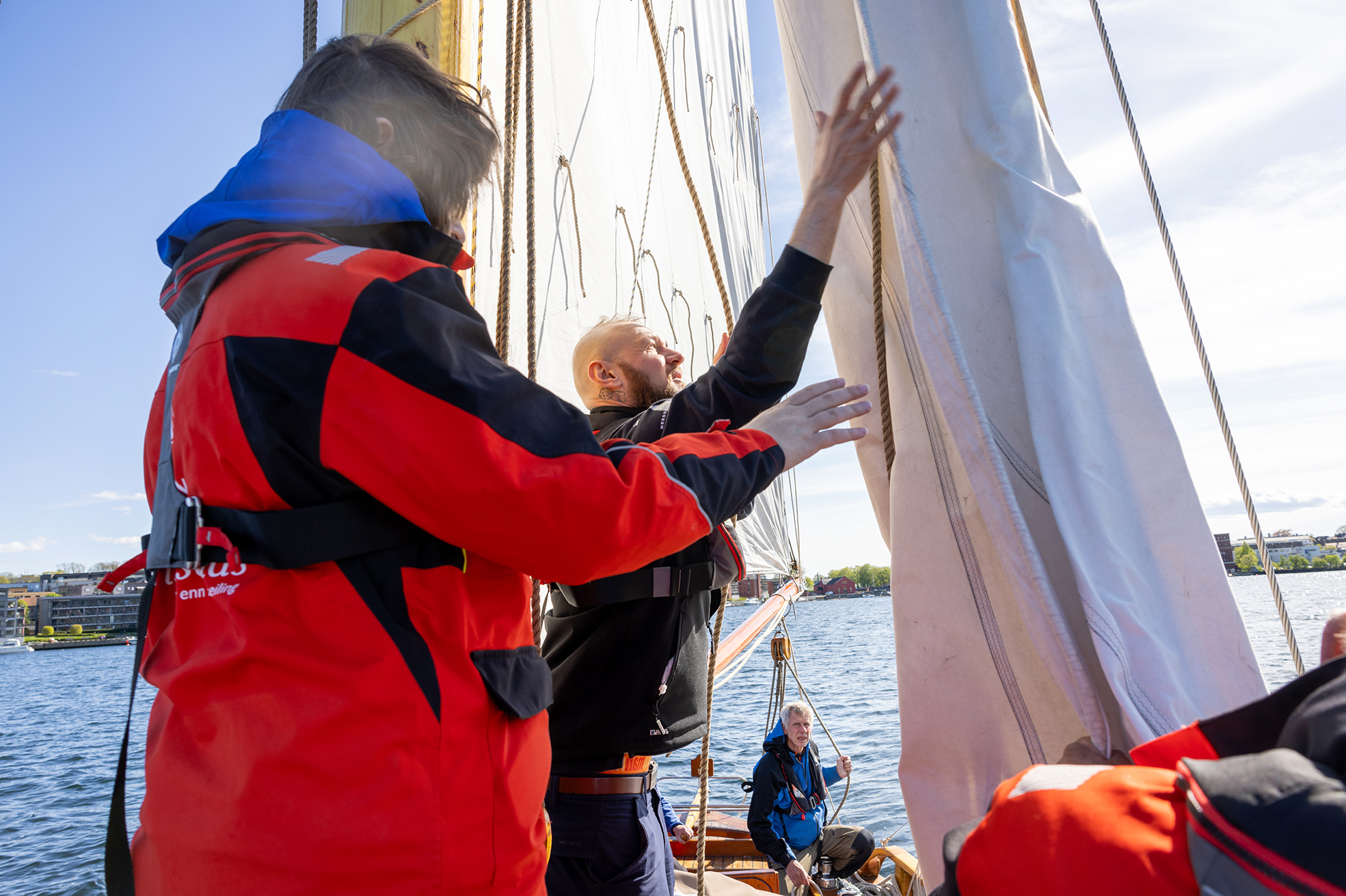 Foto: To menn som jobber med seilene. Dette er de samme to som på bildet ved siden av der de holdt på med tau.