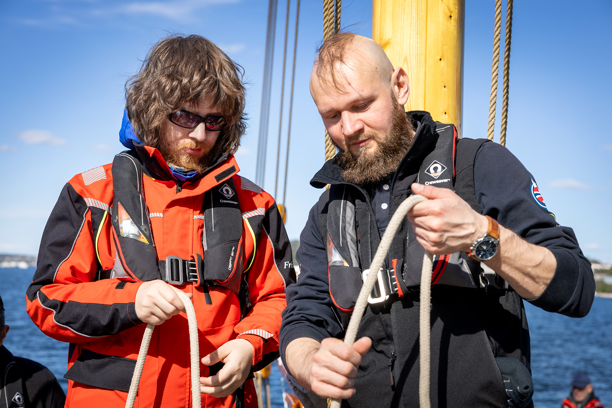 Foto: To menn står ved siden av hverandre. De holder i hvert sitt tau og den ene viser den andre no.