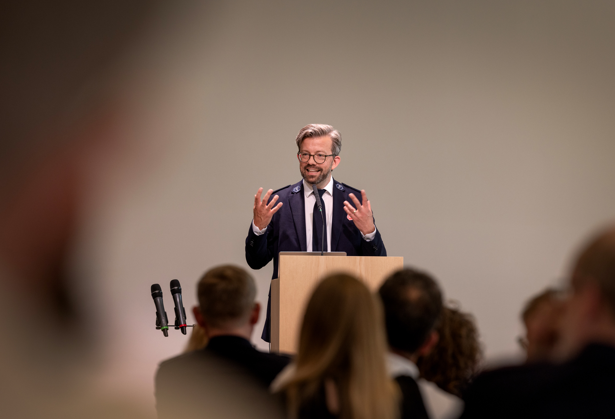 Foto: Mann i 40-årene med skjegg og briller står på talerstolen. Han har på seg uniform fra Frelsesarmeen.