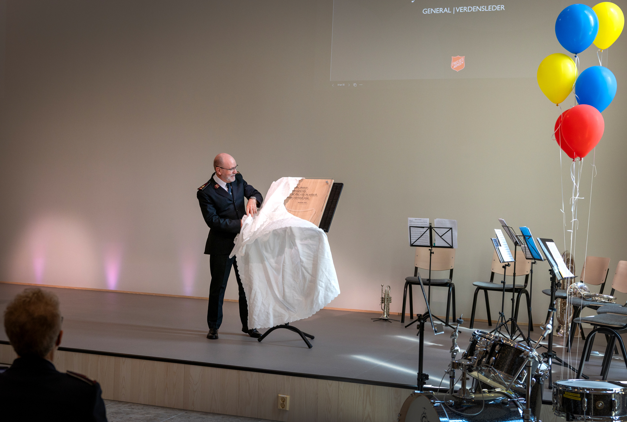 Foto: Mann i uniform drar av en duk. Under kommer det fram en plakett.