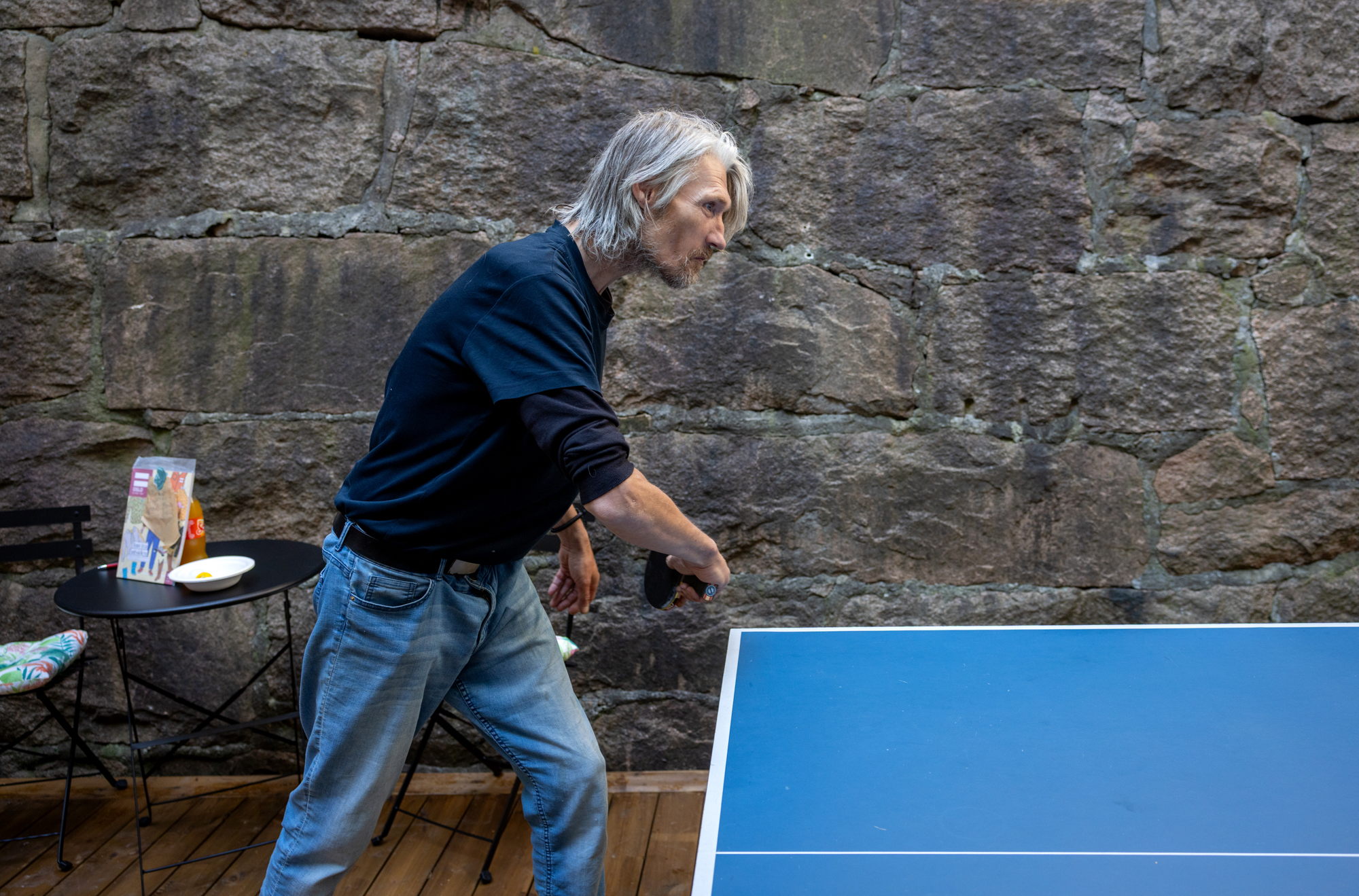 En mann står ved et bordtennisbord. Han er klar til å ta imot en serve