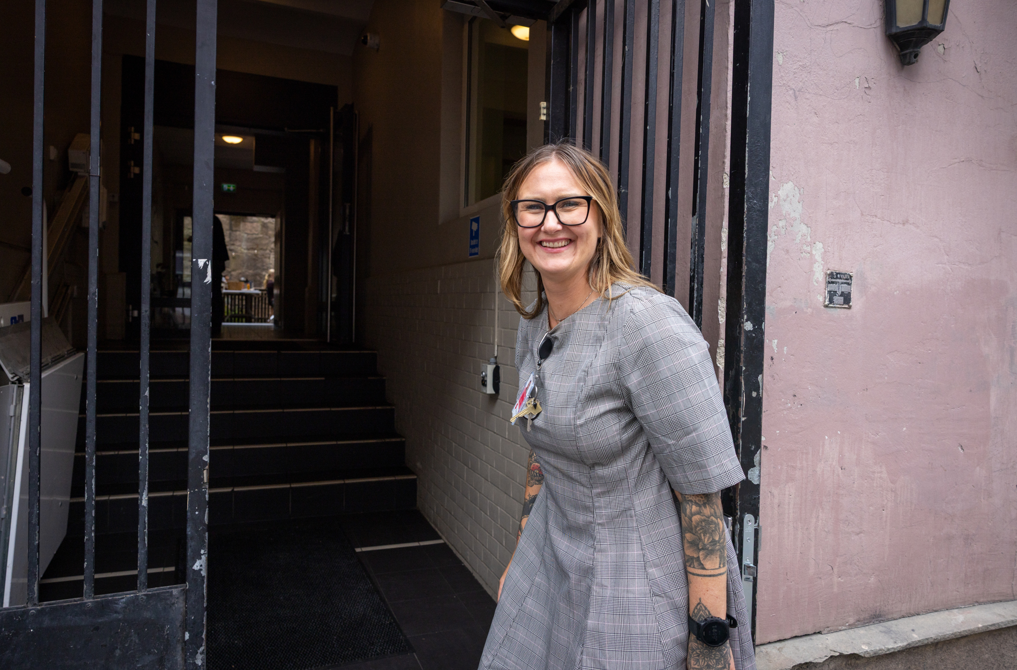Daglig leder, Silje, står ved inngangsporten til Fagerborg. Porten er åpen, hun smiler som om hun ønsker deg velkommen