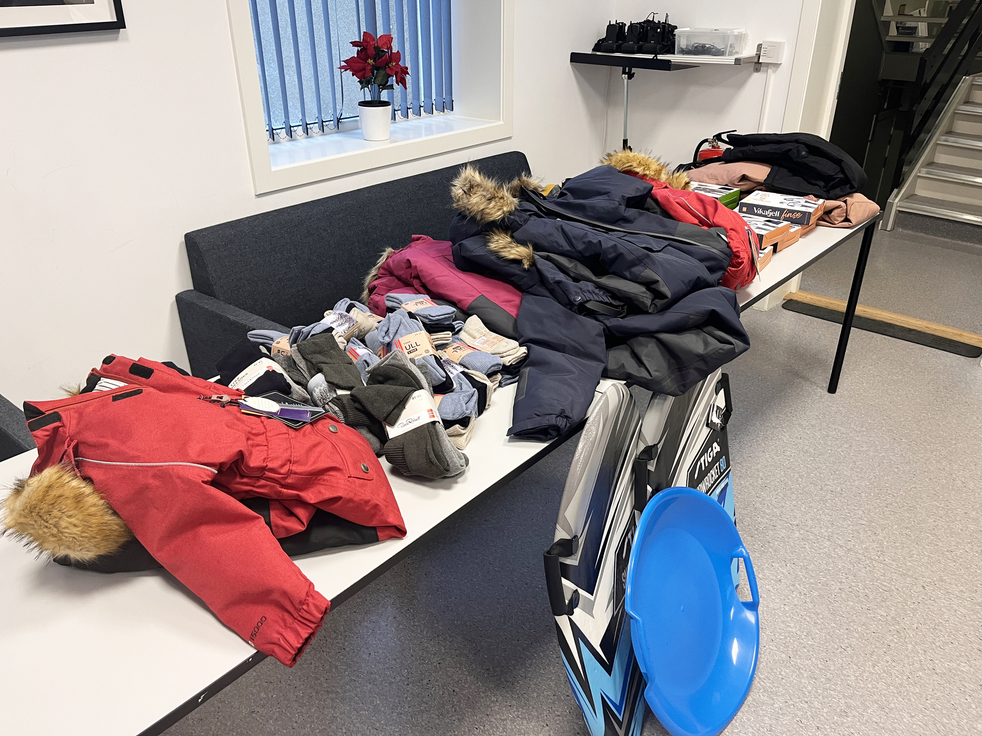 Ulltøy og varme klær ligger klart på et bord til henting av foreldre som trenger hjelp for å ha råd til vamt tøy til barna sine.