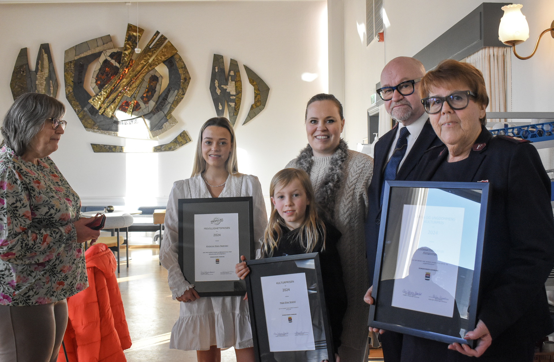 Foto: Oppstilt bilde med fire damer i ulik alder, en voksen mann og en gutt. Det blir holdt fram tre doplomer.