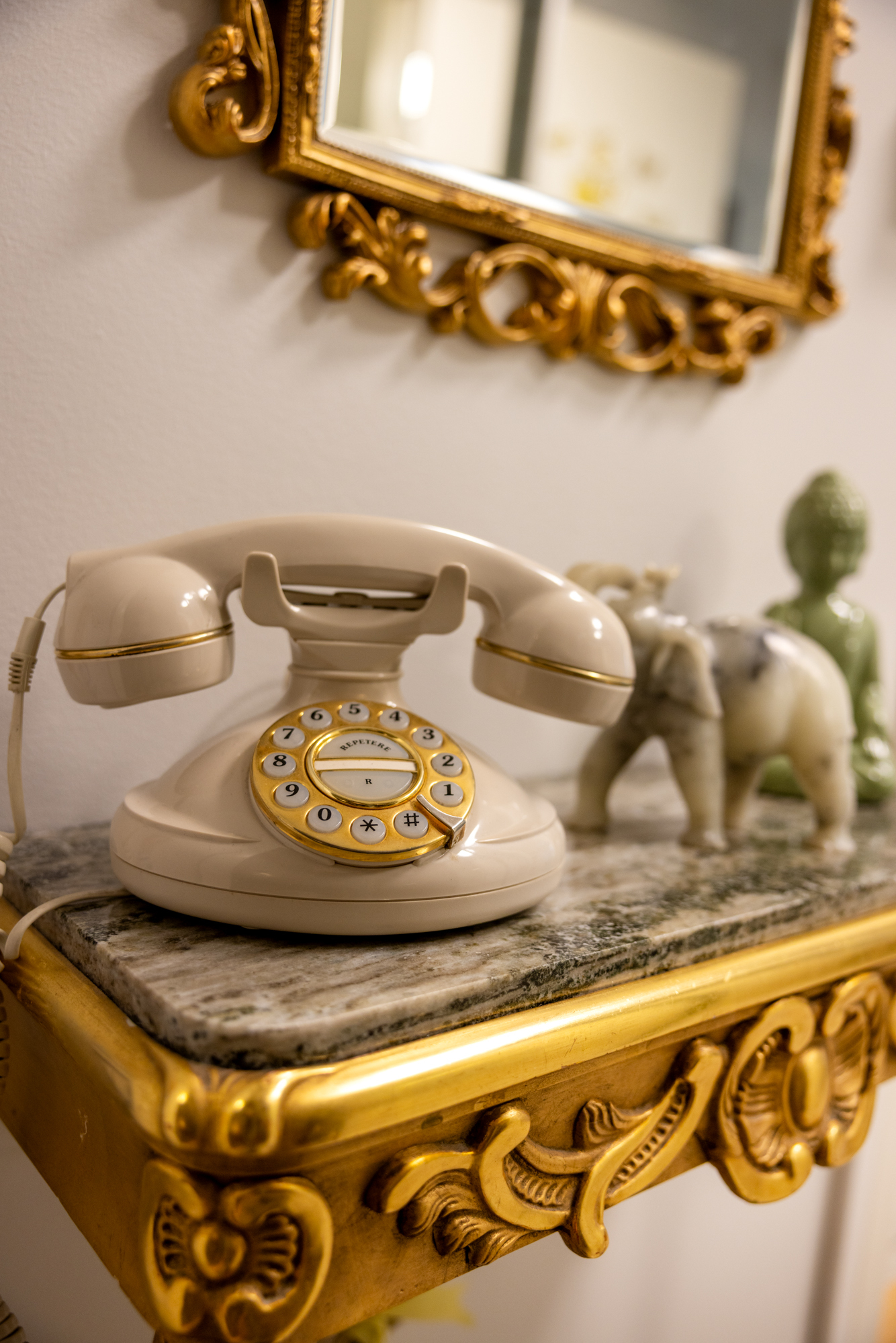 Foto: Gullkantet speil og smalt bord med glassplate og telefon oppå.