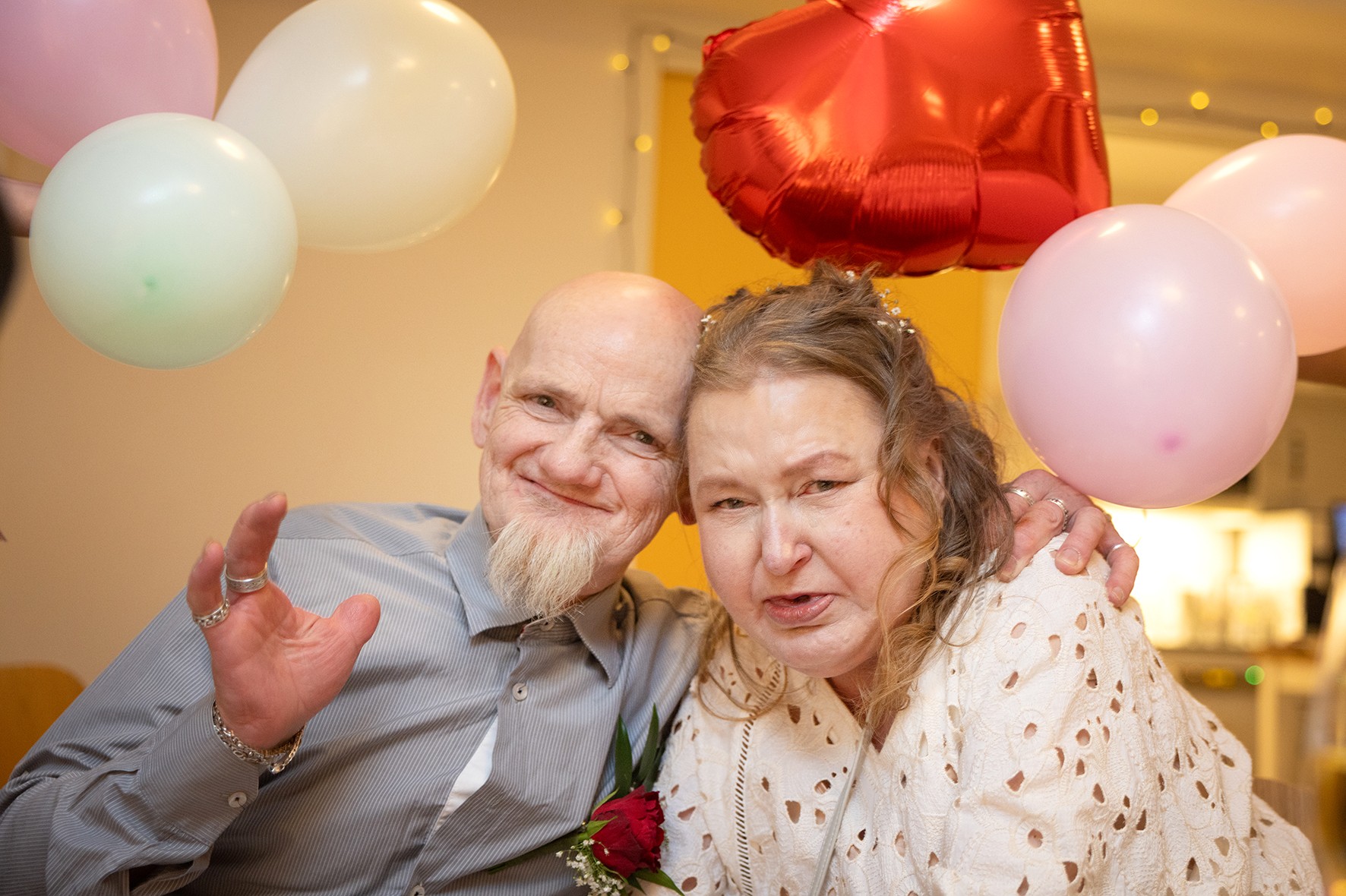 Foto: Brudgommen holder rundt sin brud. Bak dem er en rekke ballonger i hvitt, rosa og rødt.