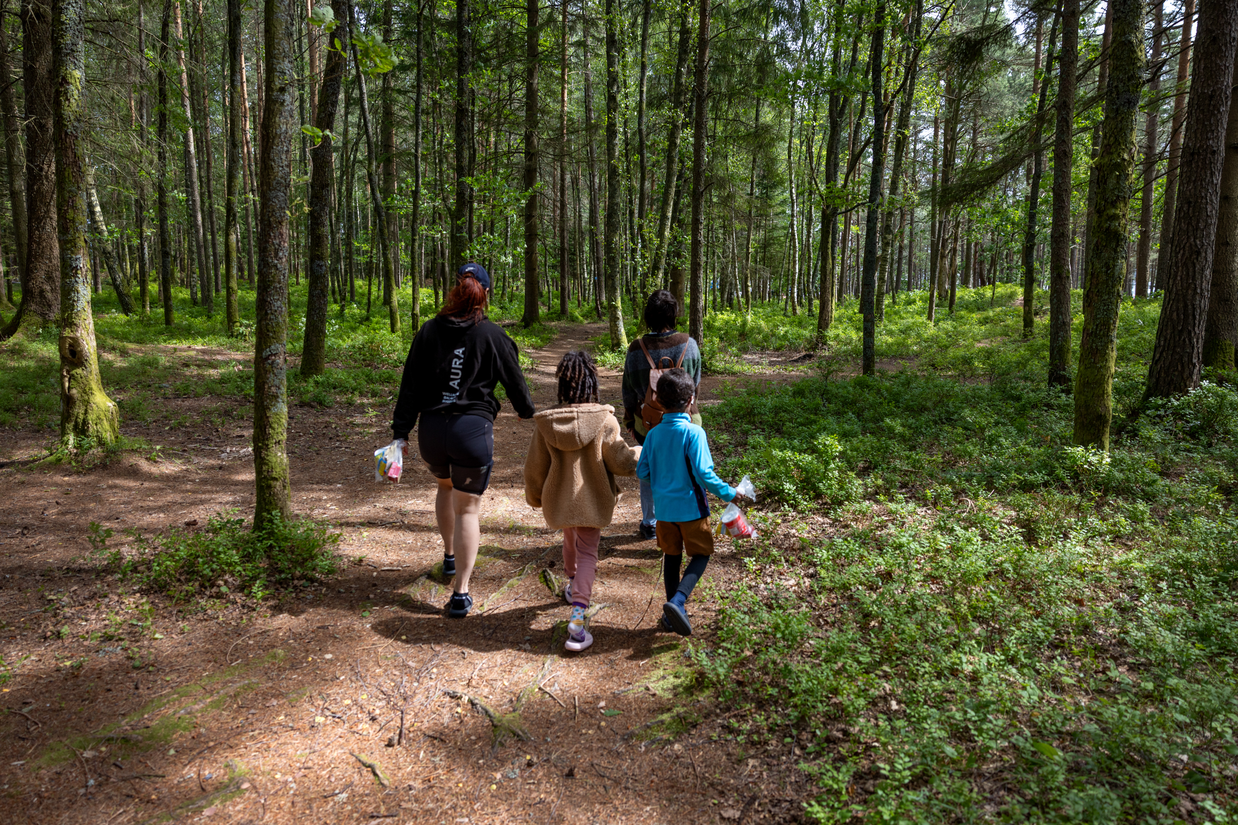 Foto: To damer og to barn går i skogen på smal grusvei. Rundt dem er det mye blåbærlyng.