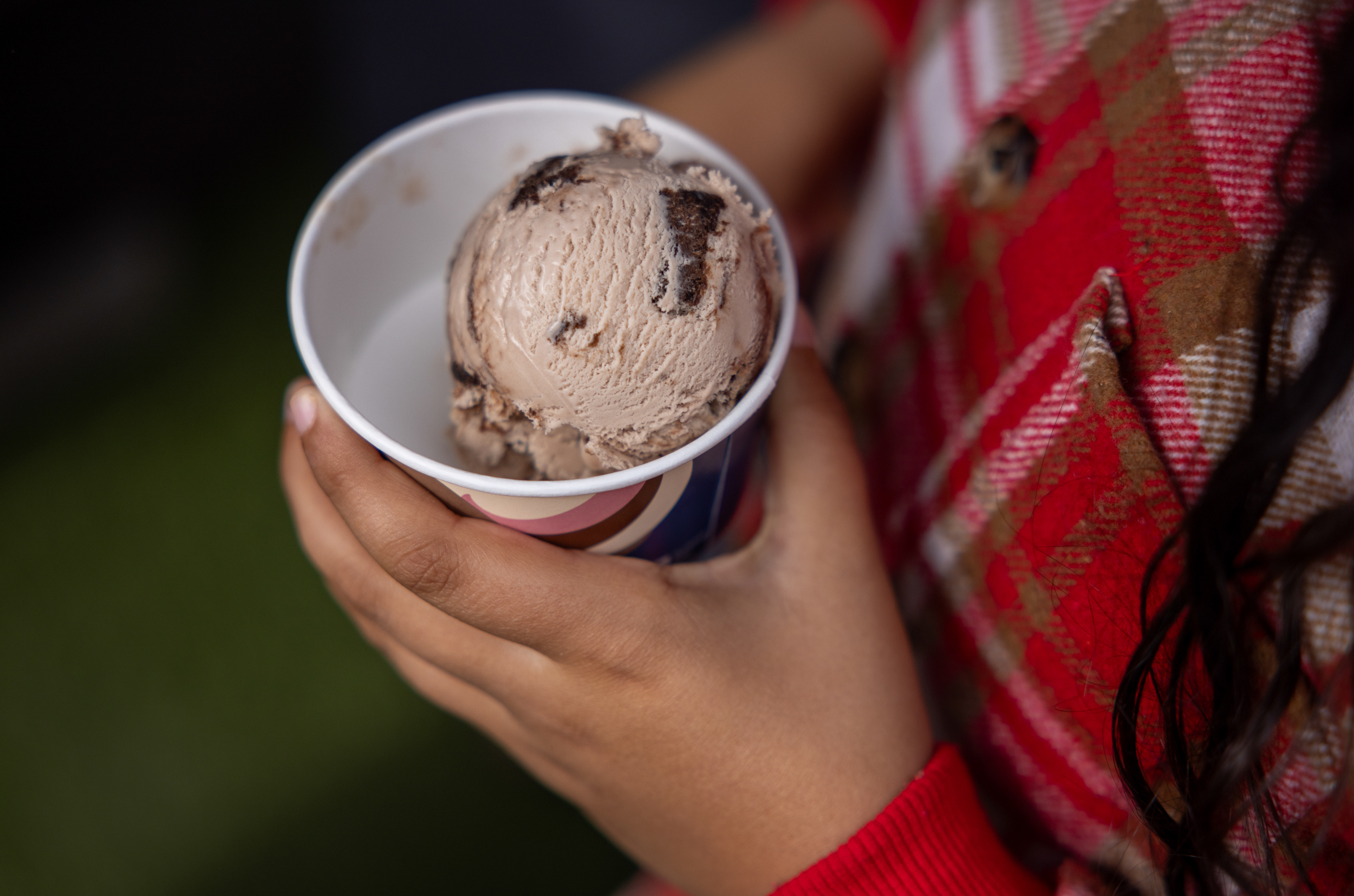 Foto: barnehender som holder fram et beger med en kule is oppi.