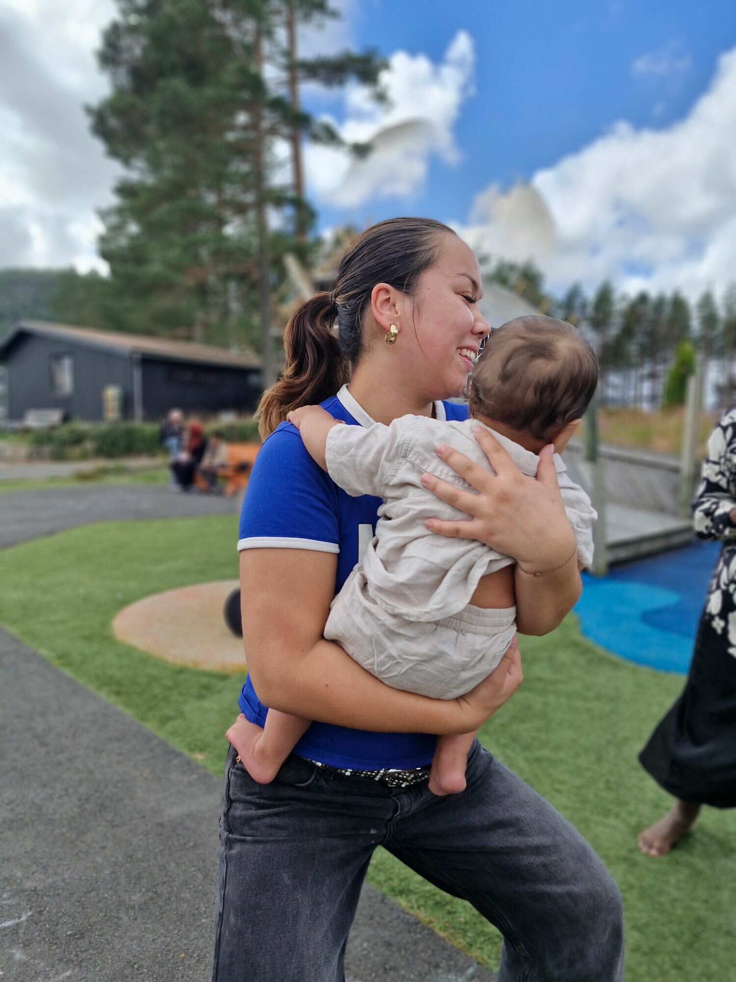 Foto: På en lekeplass bærer en tenåringsjente en baby på et halvt år på armen.