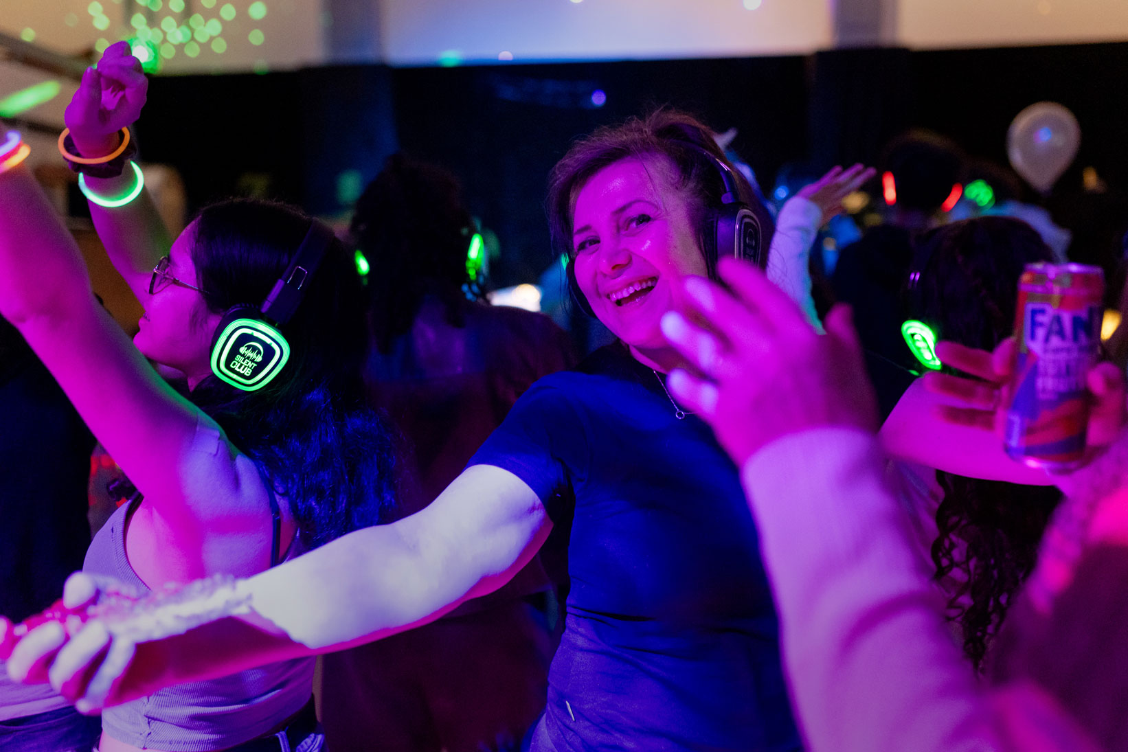 Foto: Dansende ungdommer med øreklokker i neonfarger, lysende armbånd og glowsticks i hendene