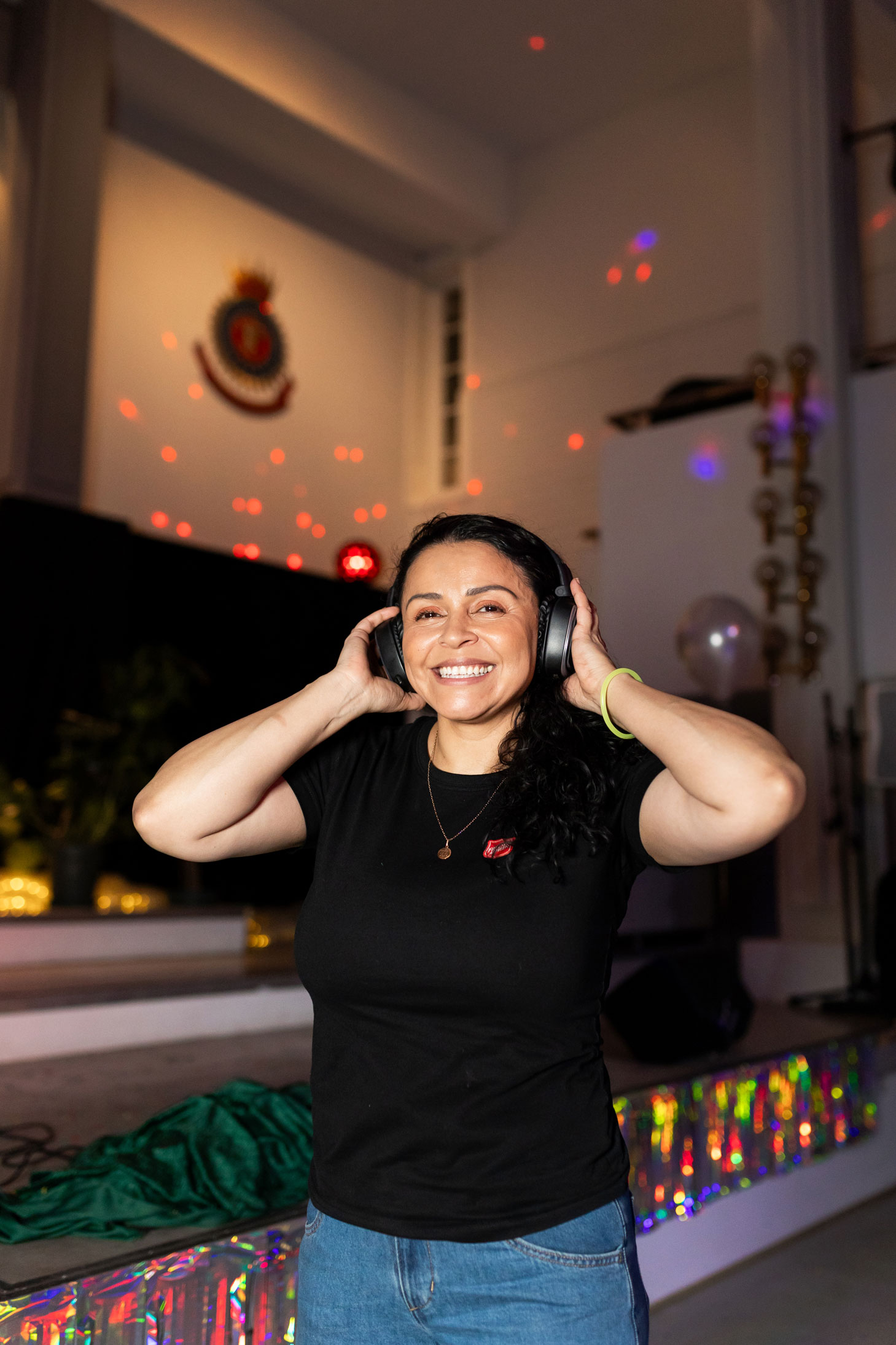 Foto: Kvinne tar på seg øreklokker og det er discolys i salen.