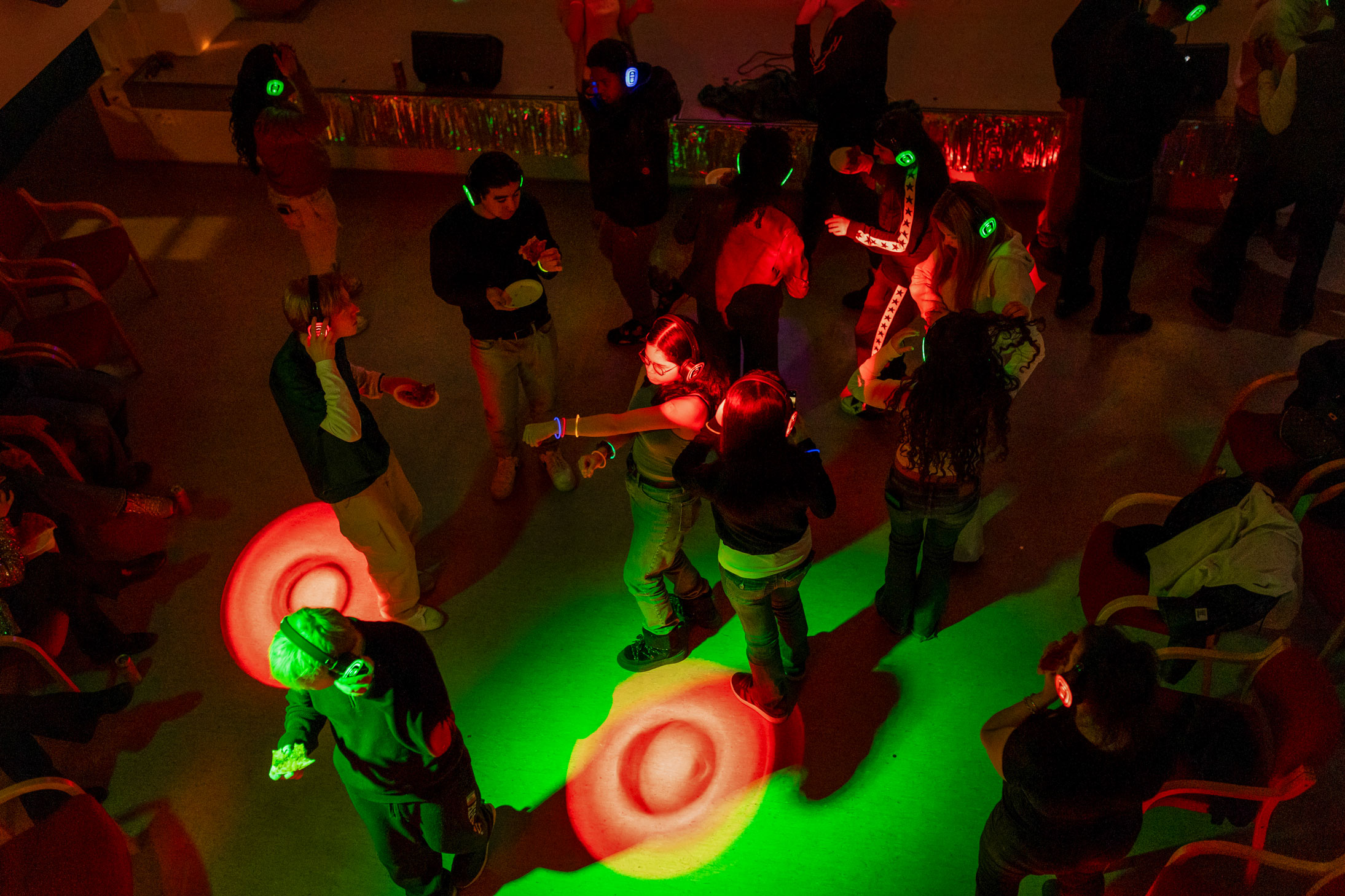 Foto: Dansegulv fullt av ungdommer som danser i rødt og grønt lus. Headsetene deres lyser opp i grønt, blått og rødt.