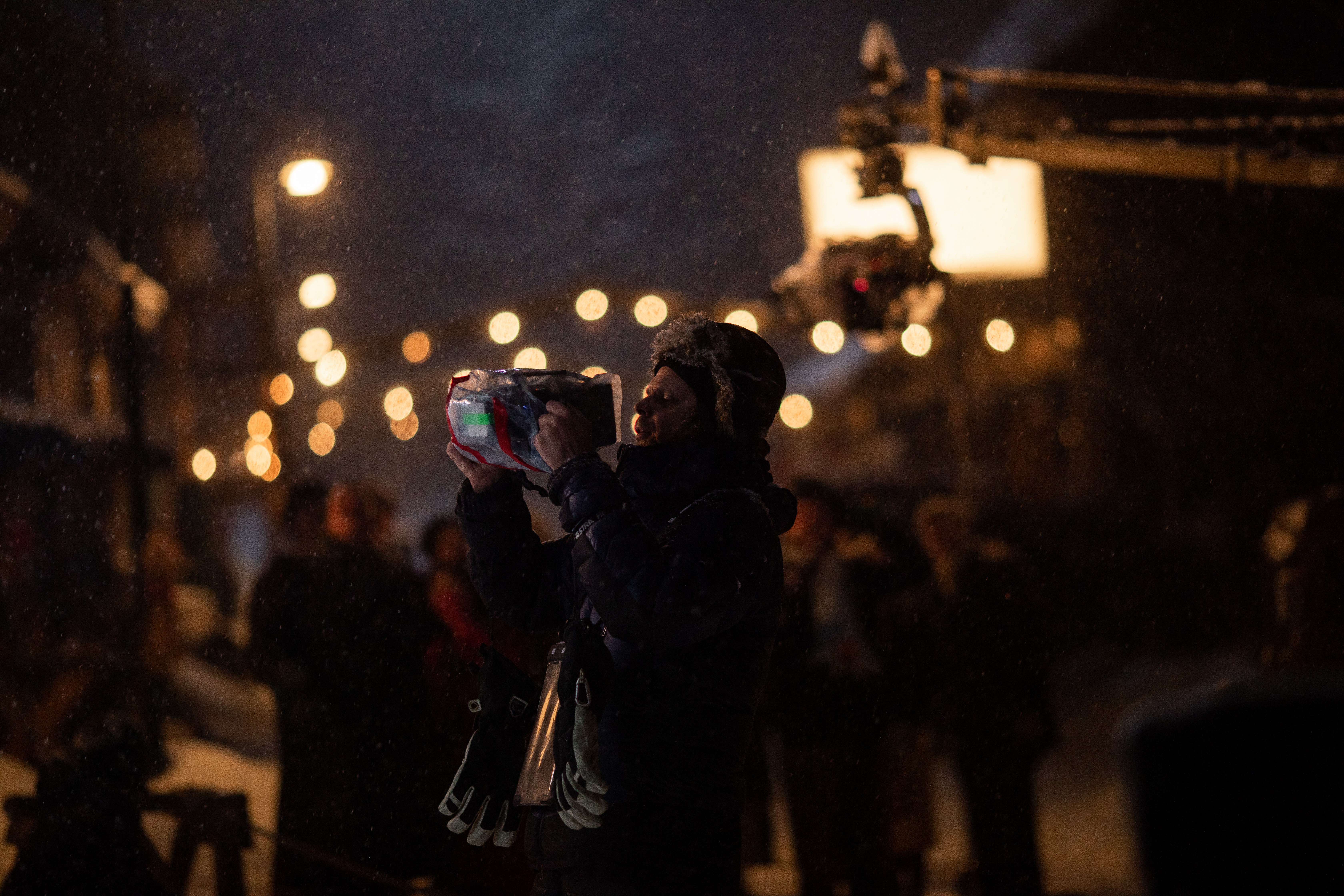 Mørk gate med tente lys. En regissør ser på en liten skjerm.