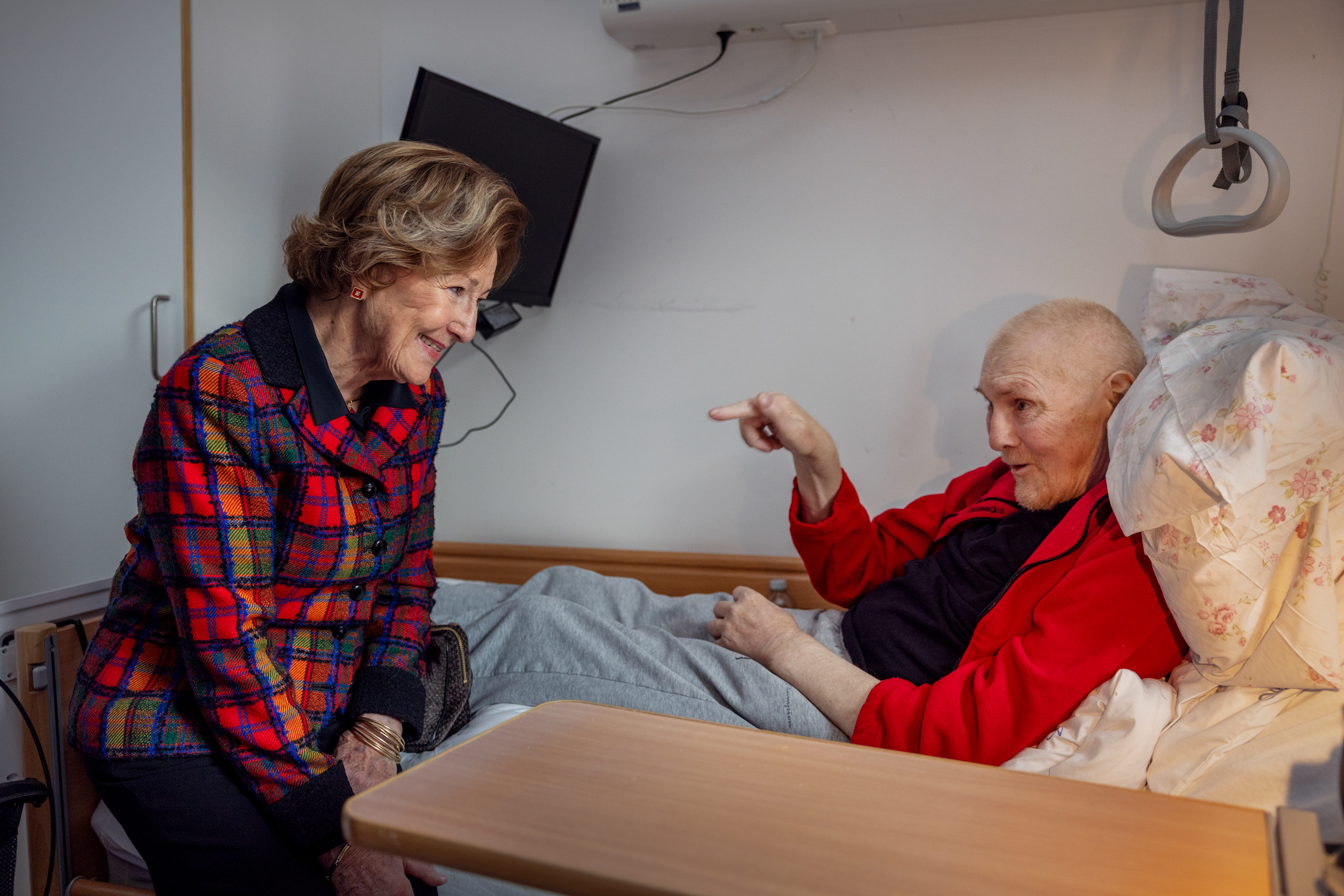 Foto: Dronningen sitter på sengen til en syk mann.