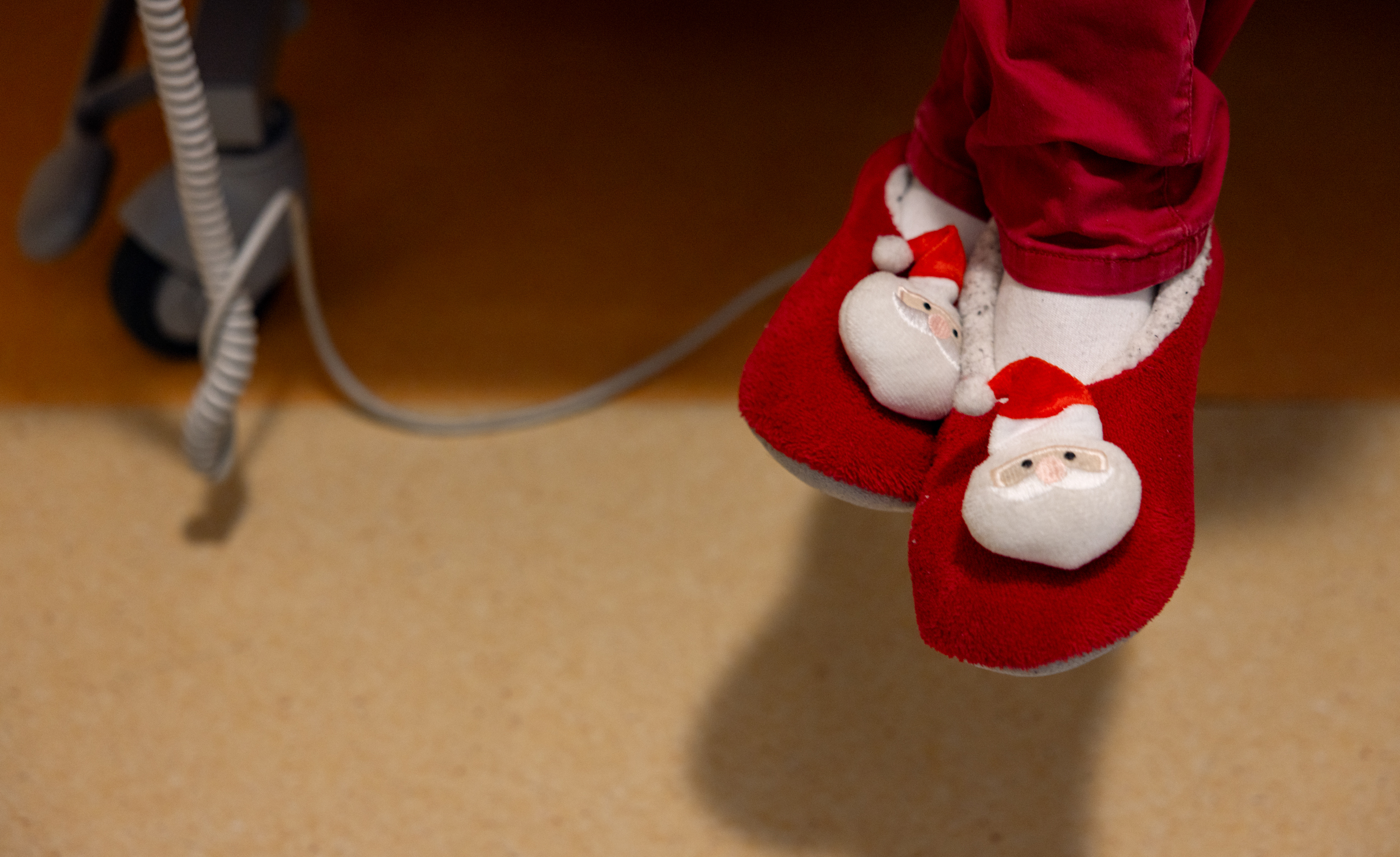 Foto: Bein med nissetøfler på dingler ned fra en sykehusseng.
