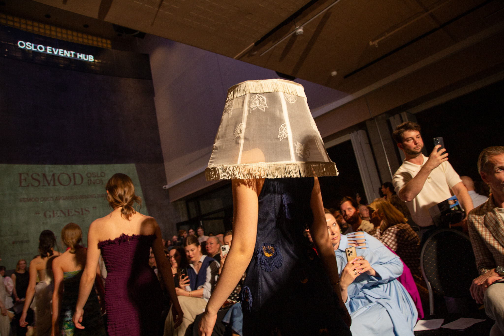 Modeller på catwalk. Ei med en stor lampeskjerm på hodet.