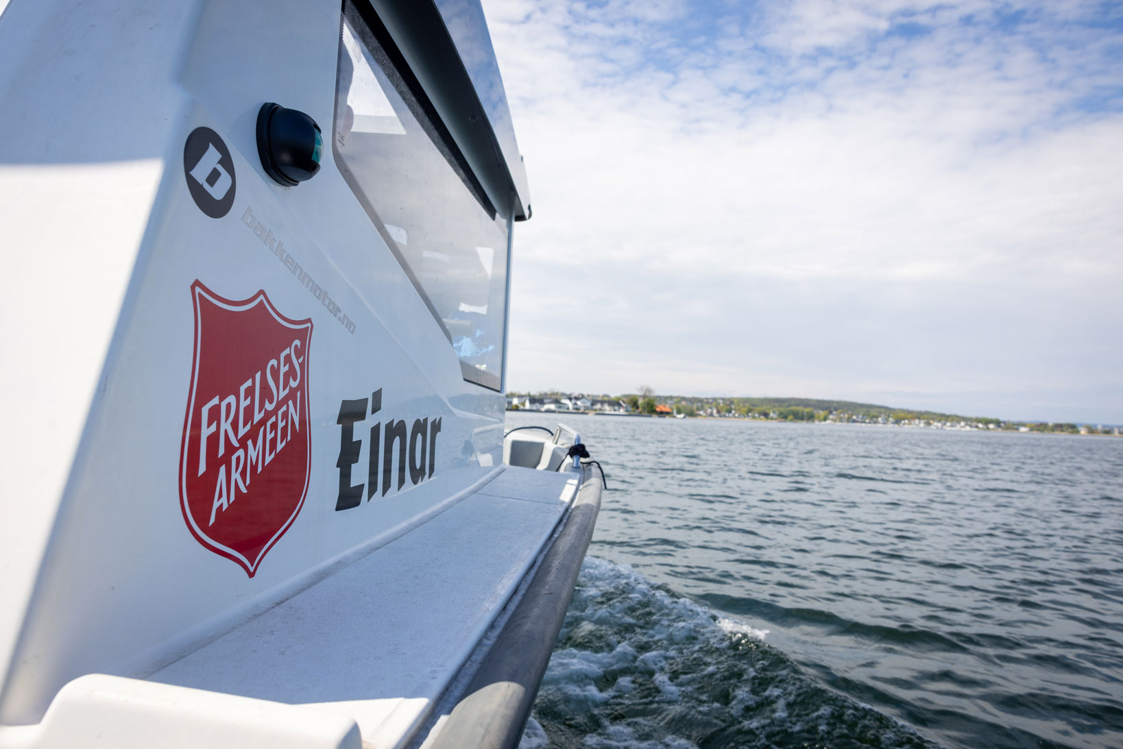 Foto: Av en båtside med logoen til Frelsesarmeen og navnet Einar ved siden av. Den ligger på sjøen.