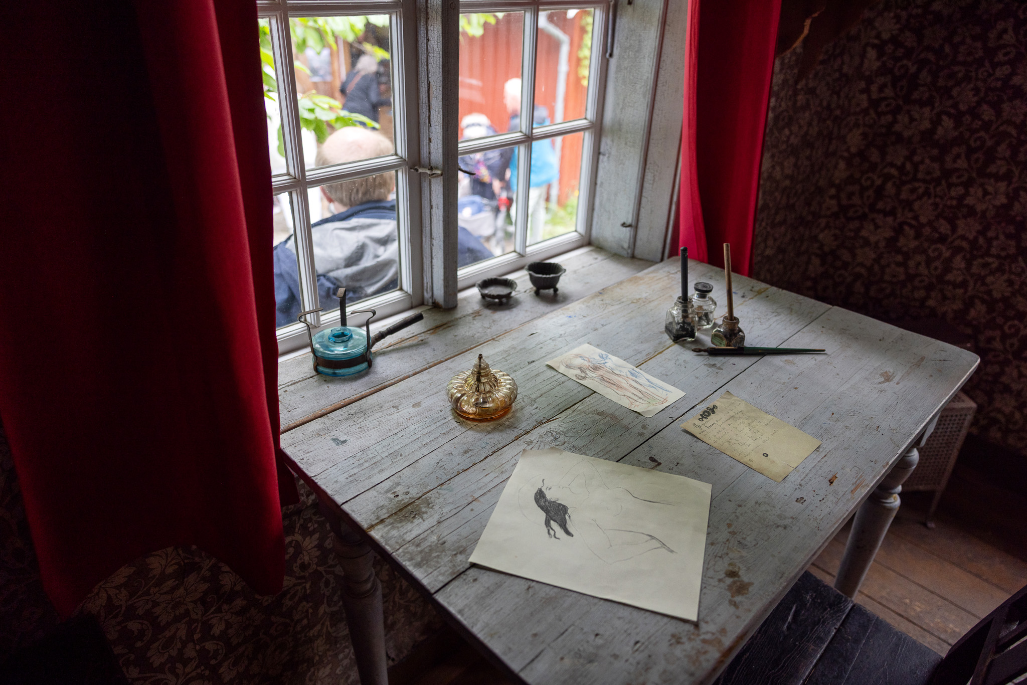 Inne i Munchs hus. En kvinne holder oppe et stort bilde av Munchs mange varianter av maleriet "Pikene på broen".