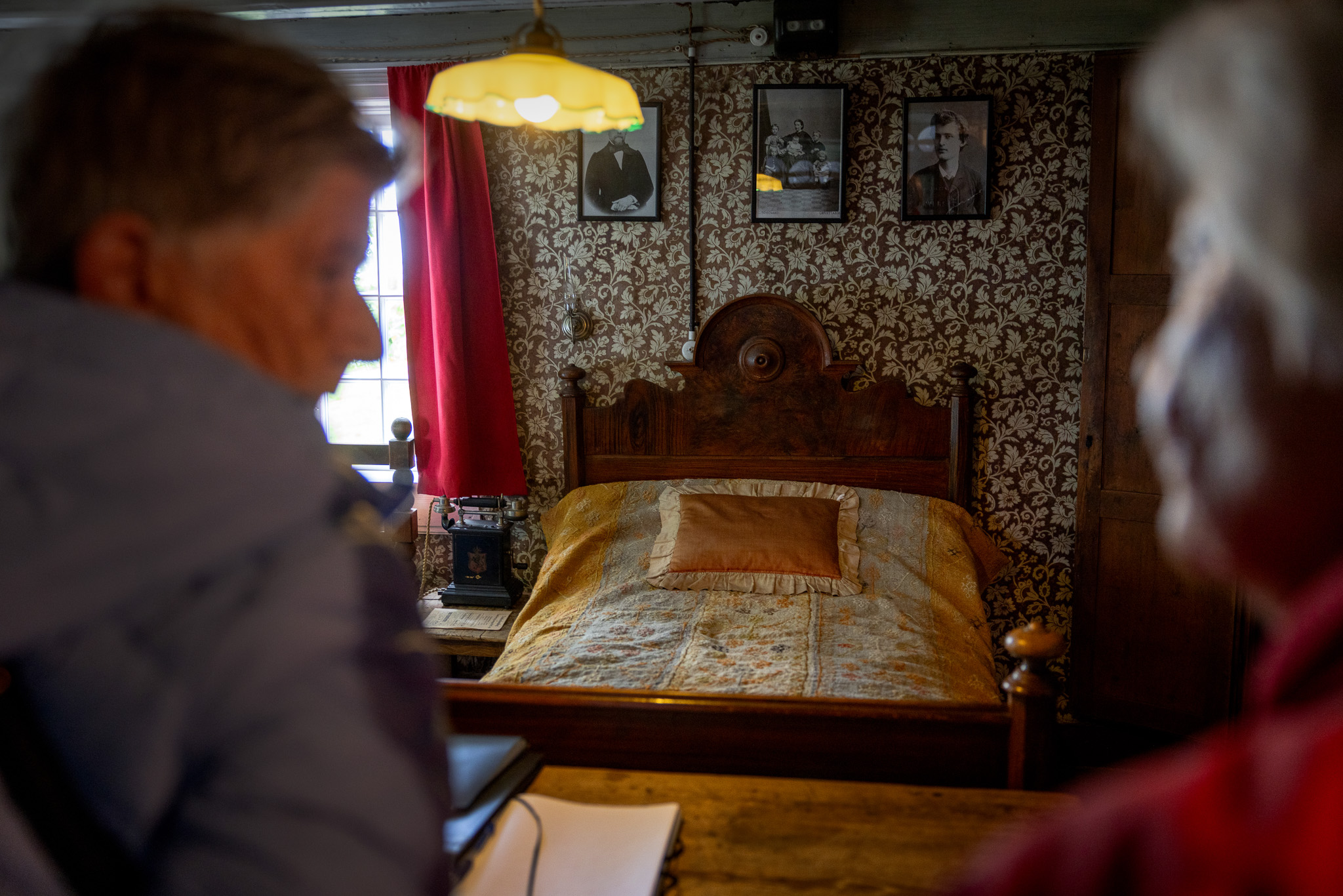 Inne i Munchs hus. En kvinne holder oppe et stort bilde av Munchs mange varianter av maleriet "Pikene på broen".