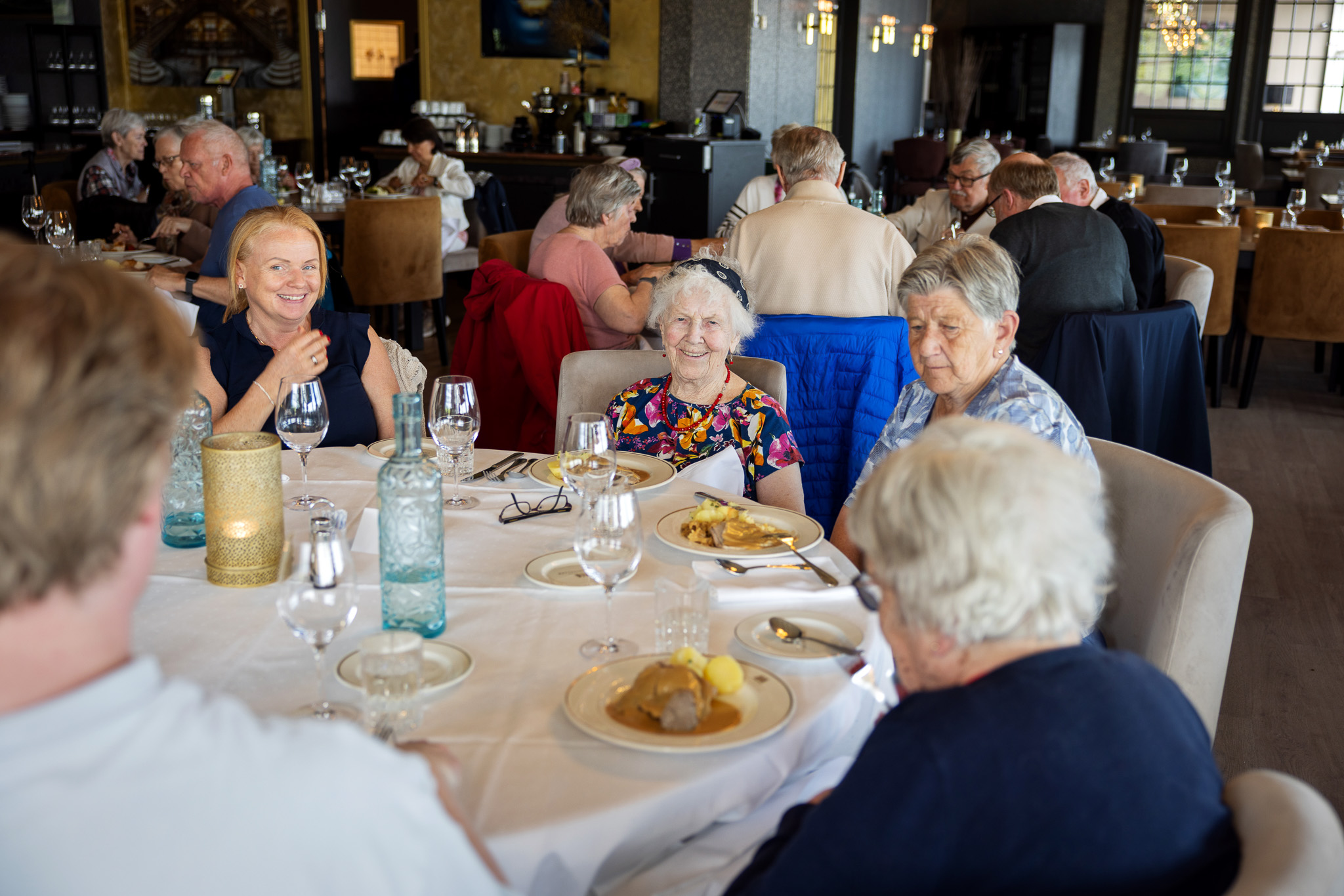 Foto: Smilende mennesker rundt runde bord i en restaurant.