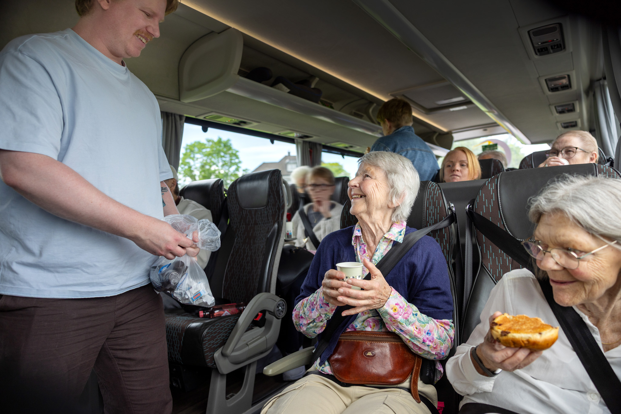 Foto: Mange eldre, blide mennesker sammen på busstur.