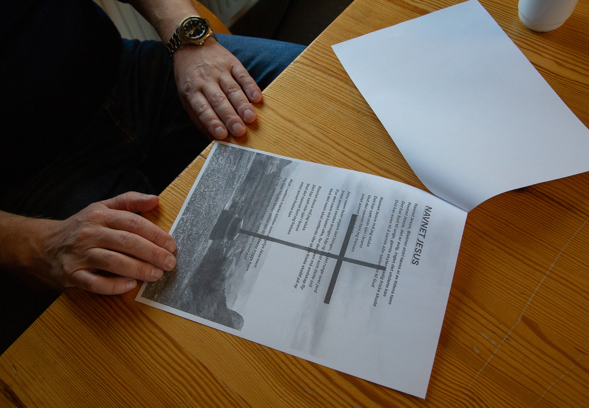 Foto: En mann holder i et ark med en sangtekst og noter på et bord.