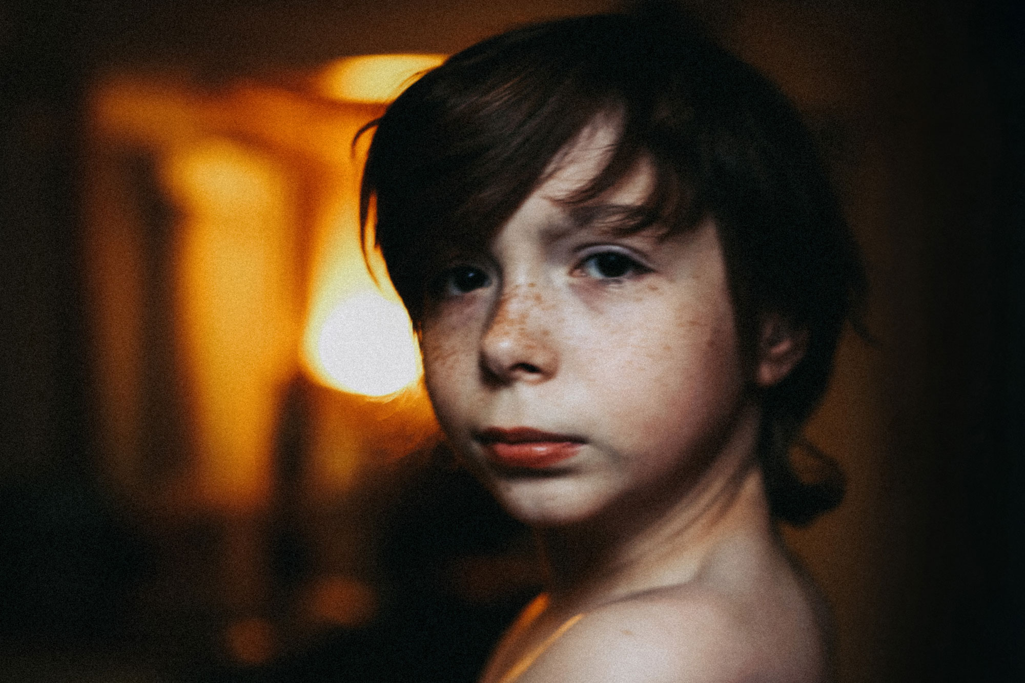 Foto: Gutt på cirka 12 år som ser i kamera. Han har mørkt halvlangt hår, og står i en mørk korridor som er opplyst i enden. Han har et intenst blikk.