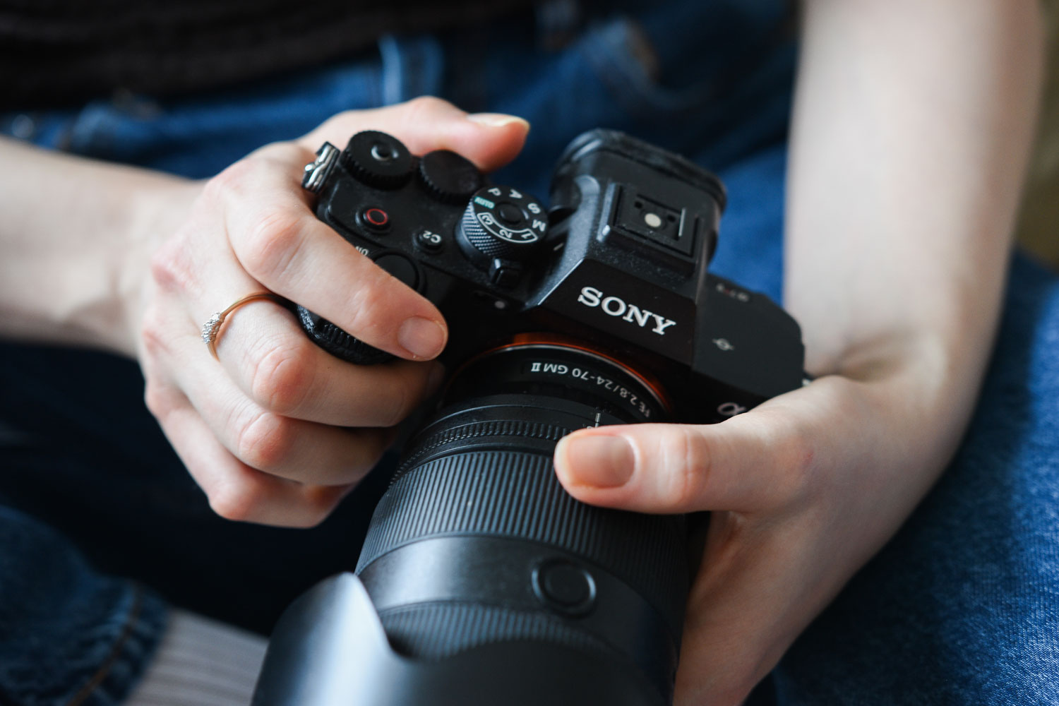 Foto: Unge, hvite kvinnehender holder et Sony kamera. Fotoapparatet ligger i fanget.