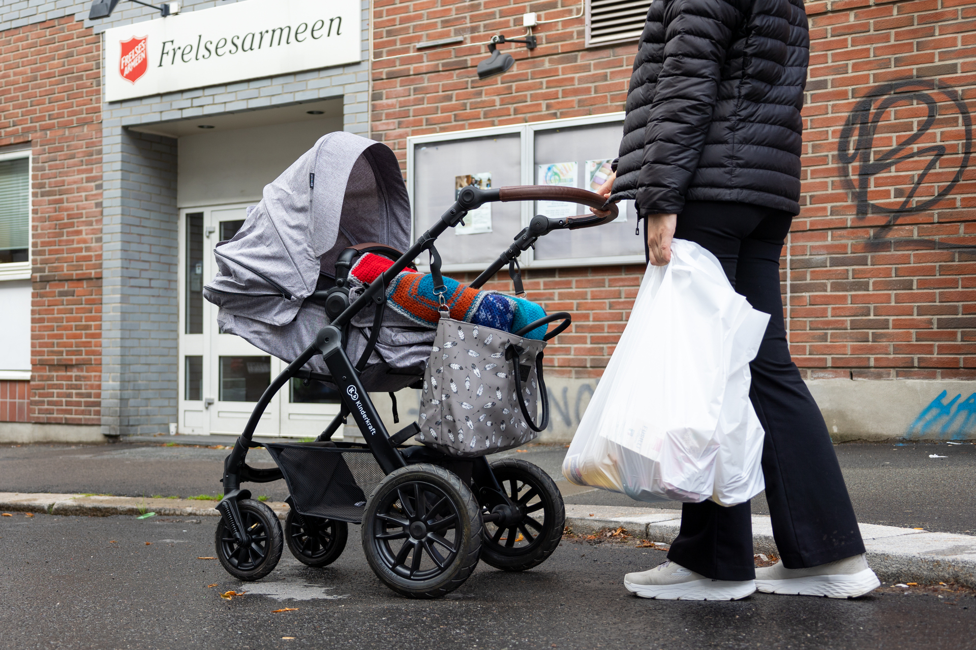 Foto: Kvinne med bæreposer og barnevogn utenfor Frelsesarmeens slumstasjon i Oslo.