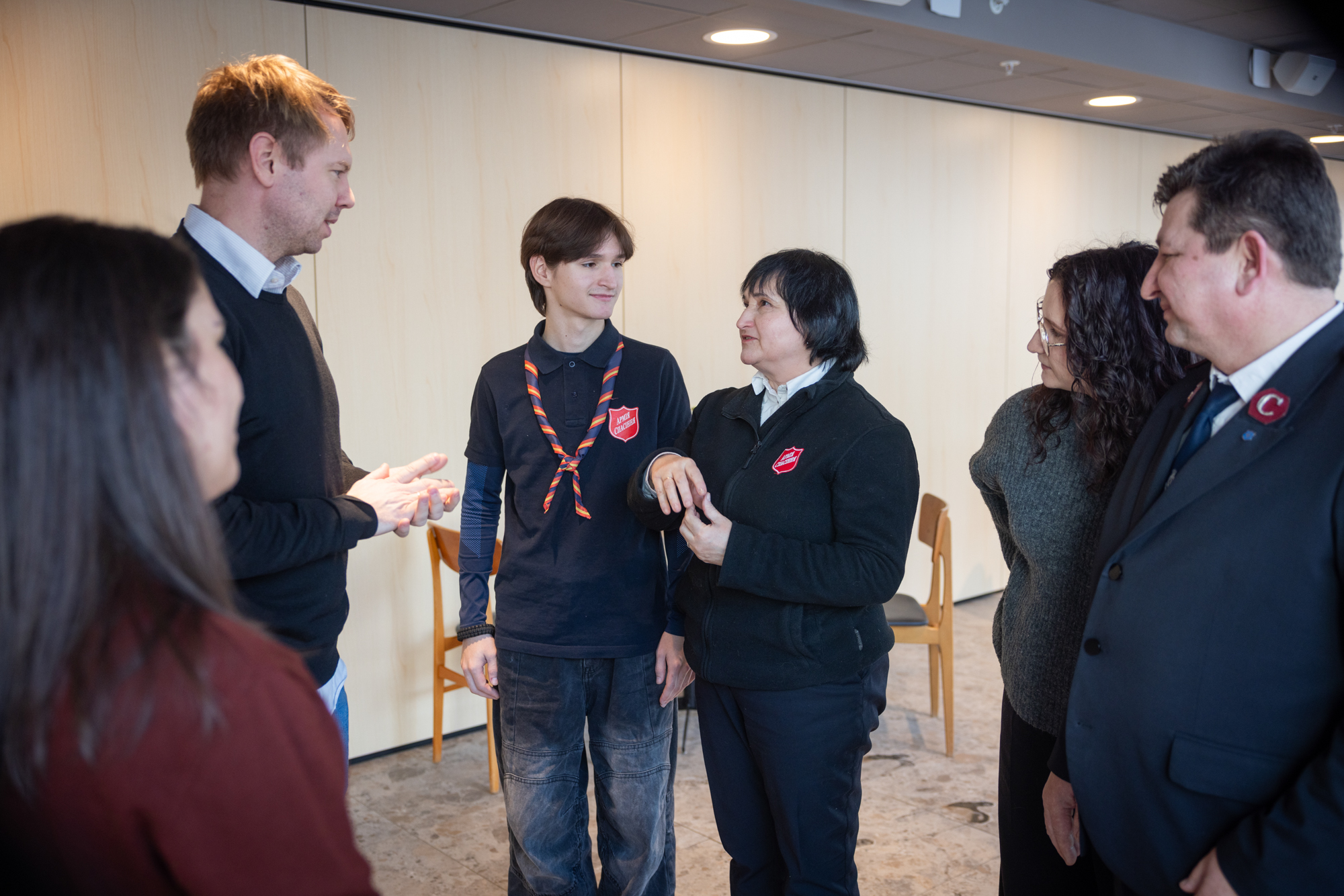 Foto: Tre kvinner og tre menn i litt ulike alder står og snakker sammen.