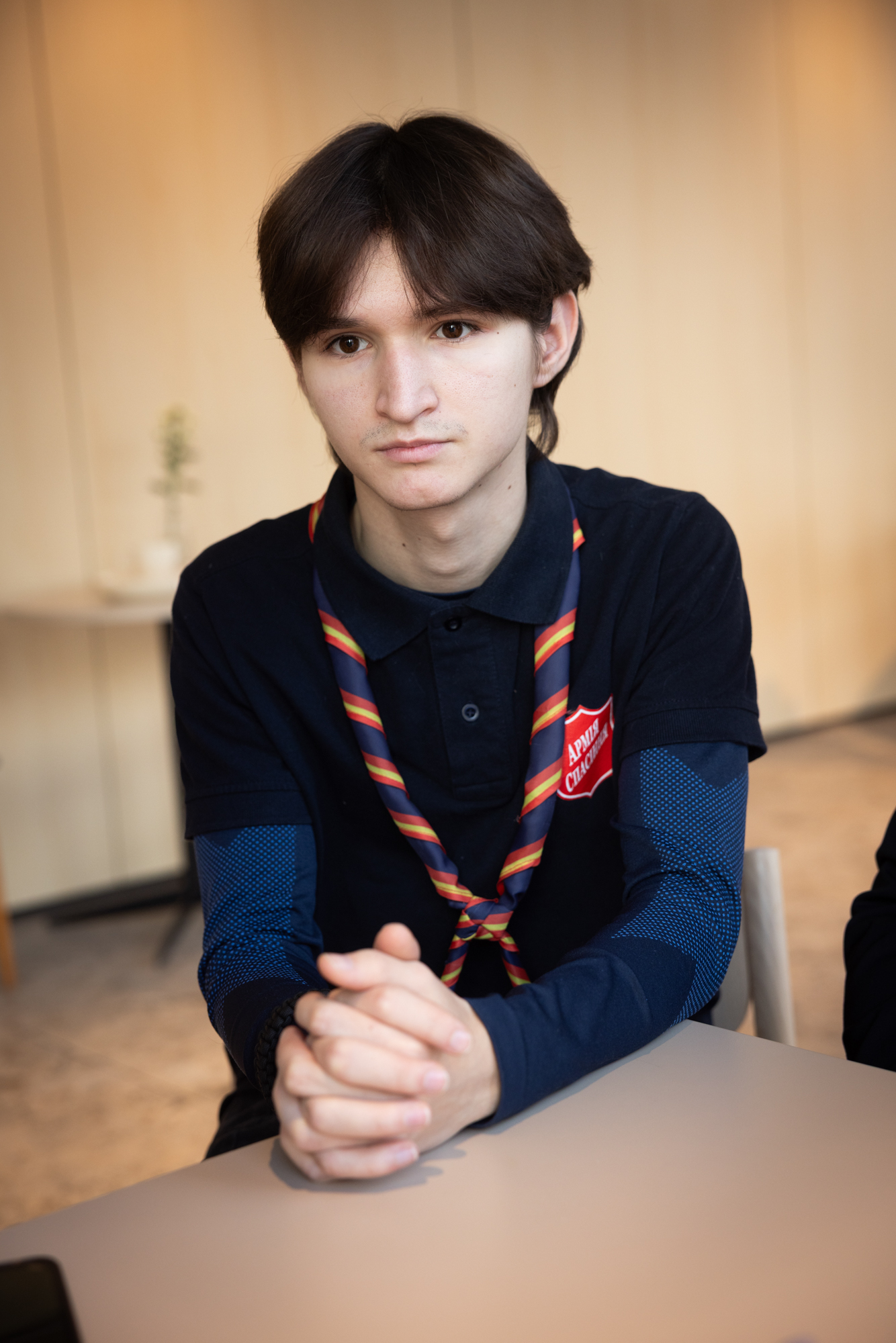 Foto: Tenåring med mørkt hår og brune øyne. Han har et fargerikt speiderskjerf om halsen.