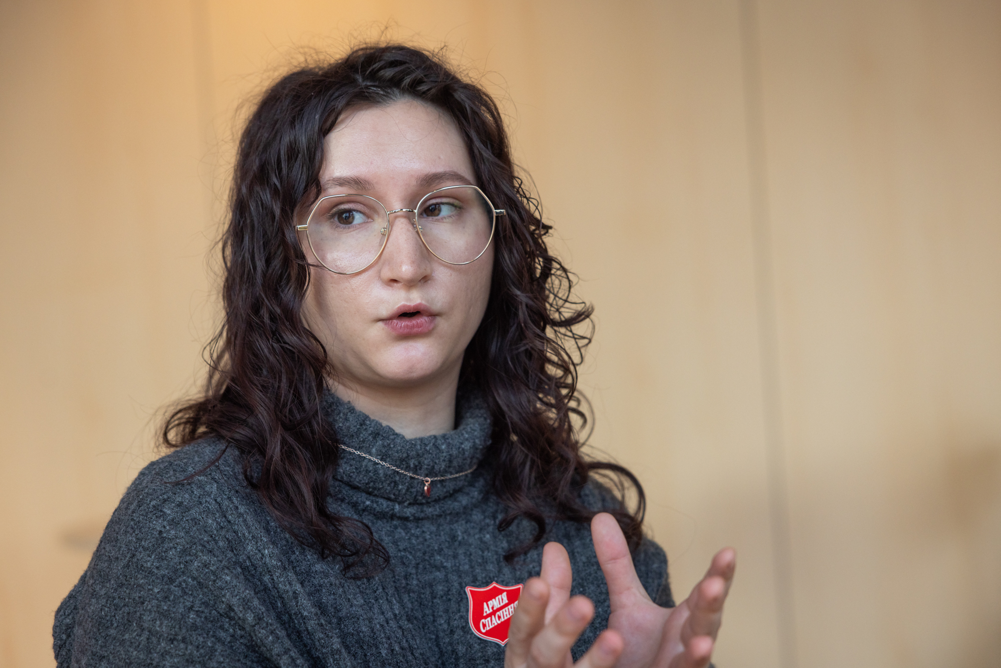 Foto: Nærbilde av ung kvinne tidlig i 20-årene med mørkt, krøllete hår og briller med innfatning i metall.