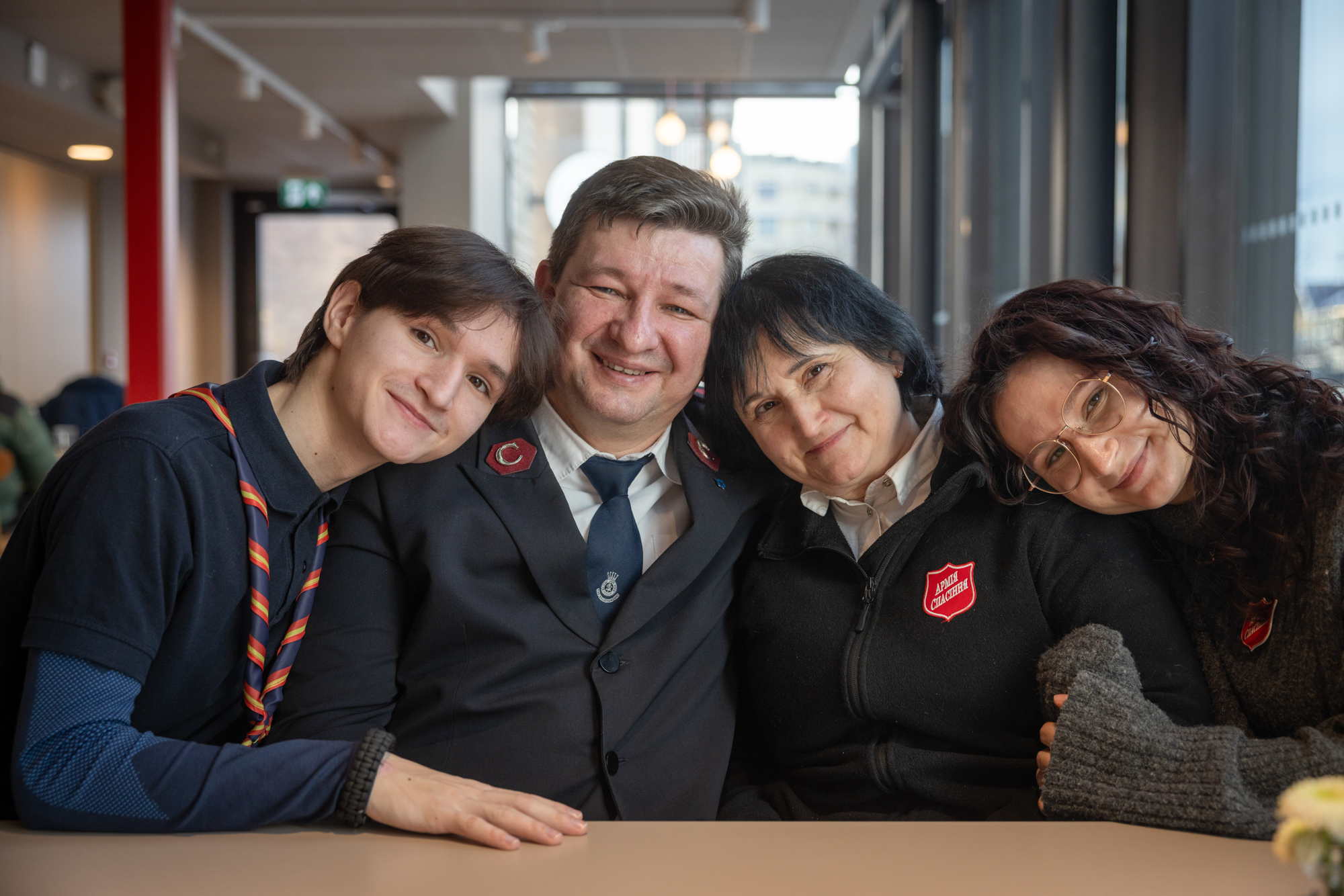 Foto: Ung kvinne og ung mann sammen med voksen kvinne og mann – begge i uniformer. Alle har mørkt hår.