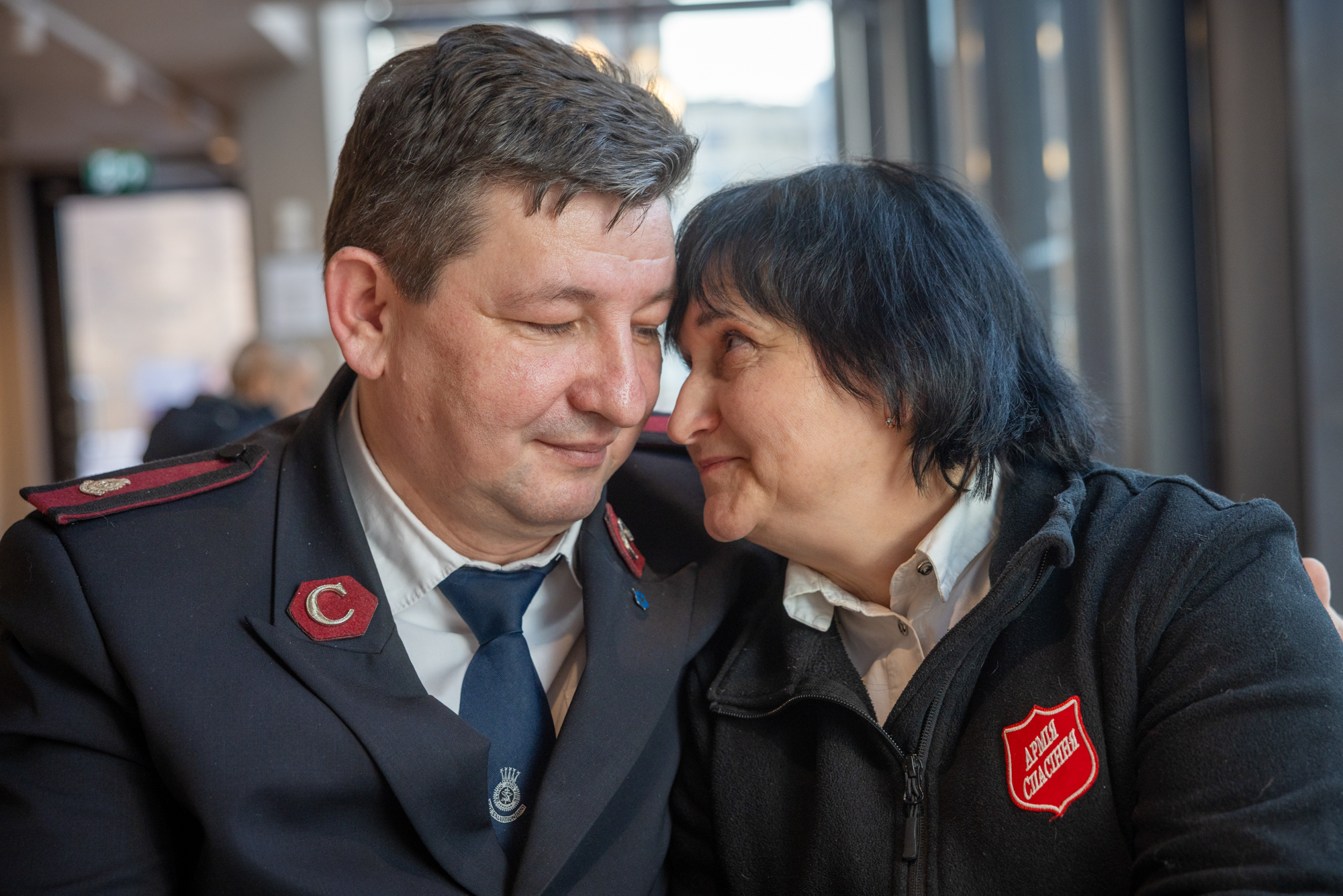 Foto: Mann og kvinne i uniform fra Frelsesarmeen sitter tett inntil hverandre. Hun ser opp på ham.