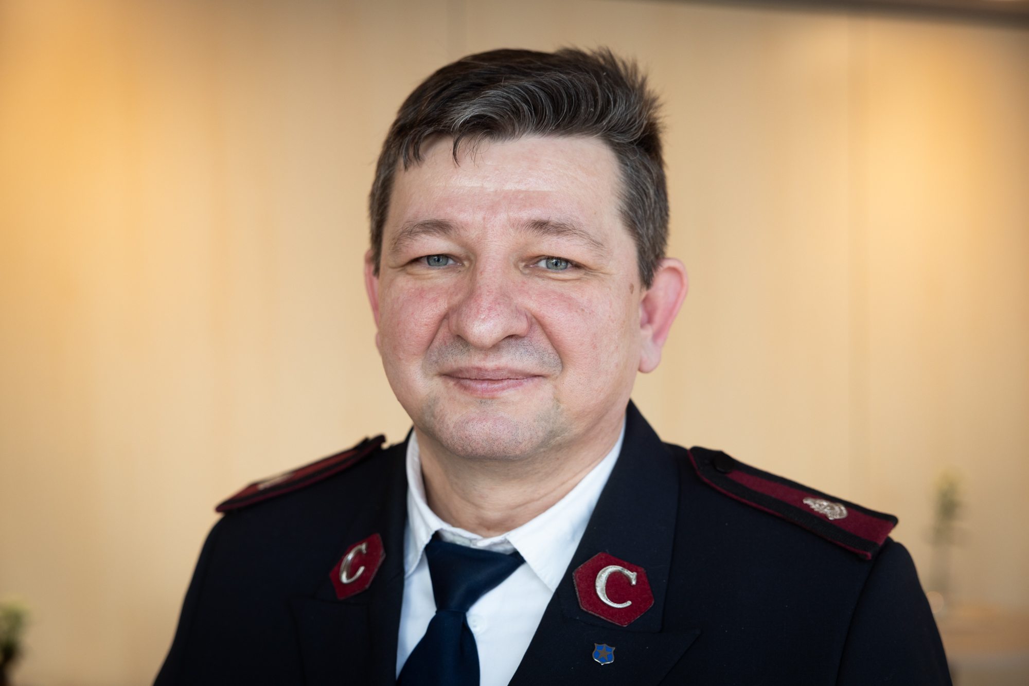 Foto: Nærbilde av mann i blå uniform. Han er i 50-årene.